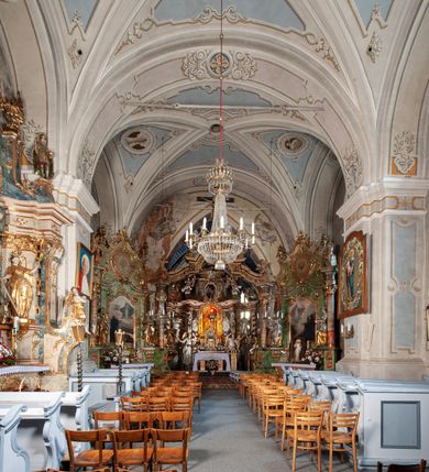 Zdjęcie nr 12: Orientowany, na rzucie prostokąta, jednonawowy, trójprzęsłowy, z węższym jednoprzęsłowym zamkniętym wielobocznie prezbiterium, przy którym od północy prostokątna zakrystia; przy nawie od południa kruchta, od północy kaplica Matki Boskiej Bolesnej, na rzucie prostokąta, ze ścianą północną wybrzuszoną w połowie długości. Od zachodu przy kaplicy wieża z prostokątną przybudówką od południa. W prezbiterium sklepienie krzyżowo-żebrowe z cylindrycznymi zwornikami wiązanymi z rodem Berzeviczych; w nawie kolebkowe z lunetami na filarach przyściennych. Arkada tęczy ostrołukowa. Zewnątrz mury opięte uskokowymi przyporami. Okna ostrołukowe dwudzielne, z maswerkami. W kruchcie południowej portal do nawy kamienny, ostrołukowy. Portal do kruchty neogotycki. Dach nad nawą dwuspadowy, na kalenicy pseudogotycka wieżyczka na sygnaturkę; dach prezbiterium wielopołaciowy.   