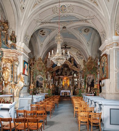 Zdjęcie nr 14: Orientowany, na rzucie prostokąta, jednonawowy, trójprzęsłowy, z węższym jednoprzęsłowym zamkniętym wielobocznie prezbiterium, przy którym od północy prostokątna zakrystia; przy nawie od południa kruchta, od północy kaplica Matki Boskiej Bolesnej, na rzucie prostokąta, ze ścianą północną wybrzuszoną w połowie długości. Od zachodu przy kaplicy wieża z prostokątną przybudówką od południa. W prezbiterium sklepienie krzyżowo-żebrowe z cylindrycznymi zwornikami wiązanymi z rodem Berzeviczych; w nawie kolebkowe z lunetami na filarach przyściennych. Arkada tęczy ostrołukowa. Zewnątrz mury opięte uskokowymi przyporami. Okna ostrołukowe dwudzielne, z maswerkami. W kruchcie południowej portal do nawy kamienny, ostrołukowy. Portal do kruchty neogotycki. Dach nad nawą dwuspadowy, na kalenicy pseudogotycka wieżyczka na sygnaturkę; dach prezbiterium wielopołaciowy.   