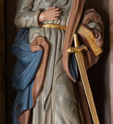 Zdjęcie nr 6: Ołtarz architektoniczny, jednokondygnacyjny, jednoosiowy, ze zwieńczeniem. Ołtarz murowany, prostopadłościenny z drewnianym antepedium ujętym drewnianą, profilowaną ramą. W polu, na błękitnym tle polichromowana para aniołków unoszących godło herbu papieskiego. Retabulum osadzone na niewysokim, zryzalitowanym uskokowo cokole. Część środkową ujmują dwie pary kolumn o cylindrycznych, kanelowanych trzonach, wspierających wyłamujące się ponad nimi, przerwane w partii architrawu i fryzu belkowanie. Zwieńczenie ujęte parą spływów wolutowych i zamknięte parą stykających się wolut, po bokach przerwany przyczółek w formie wolut. Część środkową retabulum zdobią motywy akantu i ujmuje para ażurowych uszaków. Na fryzie umieszczono kampanule. Pośrodku zwieńczenia racaille’owy kartusz, natomiast krawędzie zdobią akantowe gałązki. Szczyt w formie impostu z motywem konchy. Pole środkowe retabulum w kształcie stojącego prostokąta zamkniętego łukiem nadwieszonym z uskokami, ujęte profilowaną, złoconą ramą. W środku obraz Św. Anny, na zasuwie św. Michał Archanioł. Po bokach części środkowej para ustawionych na konsolach figur św. Piotra po lewej i św. Pawła po prawej stronie. W zwieńczeniu obraz w kształcie zbliżonym do kwadratu o wklęsłych narożach z przedstawieniem „Nawiedzenia św. Elżbiety”, po bokach para aniołków. Struktura ołtarza w kolorze brązowym, detal architektoniczny i ornamentyka złocone, rzeźby polichromowane.    