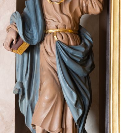 Zdjęcie nr 5: Ołtarz architektoniczny, jednokondygnacyjny, jednoosiowy, ze zwieńczeniem. Ołtarz murowany, prostopadłościenny z drewnianym antepedium ujętym drewnianą, profilowaną ramą. W polu, na błękitnym tle polichromowana para aniołków unoszących godło herbu papieskiego. Retabulum osadzone na niewysokim, zryzalitowanym uskokowo cokole. Część środkową ujmują dwie pary kolumn o cylindrycznych, kanelowanych trzonach, wspierających wyłamujące się ponad nimi, przerwane w partii architrawu i fryzu belkowanie. Zwieńczenie ujęte parą spływów wolutowych i zamknięte parą stykających się wolut, po bokach przerwany przyczółek w formie wolut. Część środkową retabulum zdobią motywy akantu i ujmuje para ażurowych uszaków. Na fryzie umieszczono kampanule. Pośrodku zwieńczenia racaille’owy kartusz, natomiast krawędzie zdobią akantowe gałązki. Szczyt w formie impostu z motywem konchy. Pole środkowe retabulum w kształcie stojącego prostokąta zamkniętego łukiem nadwieszonym z uskokami, ujęte profilowaną, złoconą ramą. W środku obraz Św. Anny, na zasuwie św. Michał Archanioł. Po bokach części środkowej para ustawionych na konsolach figur św. Piotra po lewej i św. Pawła po prawej stronie. W zwieńczeniu obraz w kształcie zbliżonym do kwadratu o wklęsłych narożach z przedstawieniem „Nawiedzenia św. Elżbiety”, po bokach para aniołków. Struktura ołtarza w kolorze brązowym, detal architektoniczny i ornamentyka złocone, rzeźby polichromowane.    