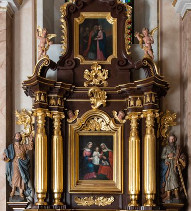 Zdjęcie nr 1: Ołtarz architektoniczny, jednokondygnacyjny, jednoosiowy, ze zwieńczeniem. Ołtarz murowany, prostopadłościenny z drewnianym antepedium ujętym drewnianą, profilowaną ramą. W polu, na błękitnym tle polichromowana para aniołków unoszących godło herbu papieskiego. Retabulum osadzone na niewysokim, zryzalitowanym uskokowo cokole. Część środkową ujmują dwie pary kolumn o cylindrycznych, kanelowanych trzonach, wspierających wyłamujące się ponad nimi, przerwane w partii architrawu i fryzu belkowanie. Zwieńczenie ujęte parą spływów wolutowych i zamknięte parą stykających się wolut, po bokach przerwany przyczółek w formie wolut. Część środkową retabulum zdobią motywy akantu i ujmuje para ażurowych uszaków. Na fryzie umieszczono kampanule. Pośrodku zwieńczenia racaille’owy kartusz, natomiast krawędzie zdobią akantowe gałązki. Szczyt w formie impostu z motywem konchy. Pole środkowe retabulum w kształcie stojącego prostokąta zamkniętego łukiem nadwieszonym z uskokami, ujęte profilowaną, złoconą ramą. W środku obraz Św. Anny, na zasuwie św. Michał Archanioł. Po bokach części środkowej para ustawionych na konsolach figur św. Piotra po lewej i św. Pawła po prawej stronie. W zwieńczeniu obraz w kształcie zbliżonym do kwadratu o wklęsłych narożach z przedstawieniem „Nawiedzenia św. Elżbiety”, po bokach para aniołków. Struktura ołtarza w kolorze brązowym, detal architektoniczny i ornamentyka złocone, rzeźby polichromowane.    