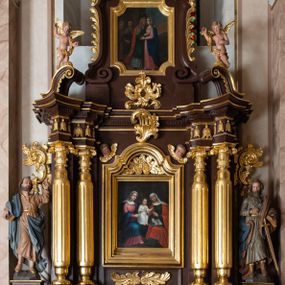 Zdjęcie nr 1: Ołtarz architektoniczny, jednokondygnacyjny, jednoosiowy, ze zwieńczeniem. Ołtarz murowany, prostopadłościenny z drewnianym antepedium ujętym drewnianą, profilowaną ramą. W polu, na błękitnym tle polichromowana para aniołków unoszących godło herbu papieskiego. Retabulum osadzone na niewysokim, zryzalitowanym uskokowo cokole. Część środkową ujmują dwie pary kolumn o cylindrycznych, kanelowanych trzonach, wspierających wyłamujące się ponad nimi, przerwane w partii architrawu i fryzu belkowanie. Zwieńczenie ujęte parą spływów wolutowych i zamknięte parą stykających się wolut, po bokach przerwany przyczółek w formie wolut. Część środkową retabulum zdobią motywy akantu i ujmuje para ażurowych uszaków. Na fryzie umieszczono kampanule. Pośrodku zwieńczenia racaille’owy kartusz, natomiast krawędzie zdobią akantowe gałązki. Szczyt w formie impostu z motywem konchy. Pole środkowe retabulum w kształcie stojącego prostokąta zamkniętego łukiem nadwieszonym z uskokami, ujęte profilowaną, złoconą ramą. W środku obraz Św. Anny, na zasuwie św. Michał Archanioł. Po bokach części środkowej para ustawionych na konsolach figur św. Piotra po lewej i św. Pawła po prawej stronie. W zwieńczeniu obraz w kształcie zbliżonym do kwadratu o wklęsłych narożach z przedstawieniem „Nawiedzenia św. Elżbiety”, po bokach para aniołków. Struktura ołtarza w kolorze brązowym, detal architektoniczny i ornamentyka złocone, rzeźby polichromowane.    