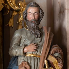 Zdjęcie nr 1: Całopostaciowa, drążona z tyłu figura św. Pawła stojącego w kontrapoście na niewysokiej postawie i zwróconego na wprost. Lekko pochyloną głowę charakteryzuje pociągła twarz o półprzymkniętych oczach, długim prostym nosie i długim, brązowym zaroście. Lekko falowane włosy opadają na kark. Święty ubrany jest w oliwkowozieloną, sięgającą do połowy łydek suknię z długimi rękawami, przewiązaną złotym paskiem oraz niebieski płaszcz o brązowym podszyciu, zarzucony na lewę ramię i opadający na plecy, osłaniając prawe biodro. Buty jasnobrązowe, z wysoką cholewą o złotym brzegu. U pasa zatknięty długi, złocony miecz. Święty prawą dłoń wspiera na piersiach, w lewej trzyma zamkniętą księgę. Draperia sukni delikatna, płaszcza o głębokich, dużych fałdach.