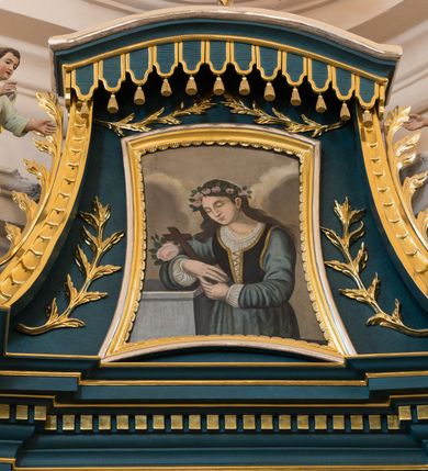 Zdjęcie nr 4: Ołtarz architektoniczny, jednokondygnacyjny, jednoosiowy, ze zwieńczeniem. Ołtarz prostopadłościenny, z drewnianą mensą i kamiennym portatylem. Antenpedium z płyciną w kształcie leżącego prostokąta, ujętą profilowaną, srebrzona ramą, z płaskorzeźbionym, złoconym i srebrzonym przedstawieniem Baranka Paschalnego na tle tarczy słonecznej. Retabulum na wysokim, zdwojonym cokole, o zryzalitowanych, uskokowych bokach, ujęte dwoma parami pilastrów i parą kolumn o kapitelach korynckich i żłobkowanych trzonach, podtrzymujących wyłamujące się ponad nimi, przerwane w partii architrawu i fryzu belkowanie z silnie wysuniętym gzymsem. Zwieńczenie ujęte parą spływów, zamknięte gzymsem w formie nadwieszonego łuku wycinkowego, flankowane fragmentami przerwanego przyczółka. Szczyt w formie promienistej glorii z motywem krzyża pośrodku. Górny cokół retabulum zdobiony motywem przewiązanych wstęgą kampanulli, pośrodku konsolka z polem w kształcie stojącego prostokąta zamkniętego półkoliście z monogramem chrystologicznym (XP AΩ). U góry środkowej części retabulum ornamentyka roślinna z motywem rocaille'u. Partie fryzu zdobione motywem rozet, w partii gzymsu ornament kostkowy. Zwieńczenie dekorowane motywem gałązek liściastych, krawędzie spływów ornamentem cekinowym, w górnej partii lambrekin. Całość flankuje para wazonów. Pole środkowe retabulum w formie prostokątnej niszy zamkniętej konchą o wykroju łuku półkolistego nadwieszonego, ujętej profilowaną, złoconą i srebrzoną ramą. Ścianki niszy zdobione grawerowaną dekoracją stylizowanych motywów roślinnych. Wewnątrz rzeźba Najświętszego Serce Jezusa. W zwieńczeniu pole w kształcie stojącego trapezu z wklęsło-wypukłymi bokami, ujęte profilowaną, złoconą i srebrzoną ramą. Wewnątrz obraz ze św. Rozalią. Na fragmentach przerwanego przyczółka para klęczących aniołków.
 Struktura polichromowana w kolorze ciemnego turkusu. Ołtarz i konsolka retabulum marmoryzowane z odcieniach szarości i brązów. Detal architektoniczny i ornamentyka złocone i srebrzone.     
