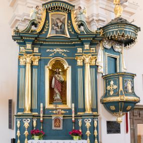 Zdjęcie nr 1: Ołtarz architektoniczny, jednokondygnacyjny, jednoosiowy, ze zwieńczeniem. Ołtarz prostopadłościenny, z drewnianą mensą i kamiennym portatylem. Antenpedium z płyciną w kształcie leżącego prostokąta, ujętą profilowaną, srebrzona ramą, z płaskorzeźbionym, złoconym i srebrzonym przedstawieniem Baranka Paschalnego na tle tarczy słonecznej. Retabulum na wysokim, zdwojonym cokole, o zryzalitowanych, uskokowych bokach, ujęte dwoma parami pilastrów i parą kolumn o kapitelach korynckich i żłobkowanych trzonach, podtrzymujących wyłamujące się ponad nimi, przerwane w partii architrawu i fryzu belkowanie z silnie wysuniętym gzymsem. Zwieńczenie ujęte parą spływów, zamknięte gzymsem w formie nadwieszonego łuku wycinkowego, flankowane fragmentami przerwanego przyczółka. Szczyt w formie promienistej glorii z motywem krzyża pośrodku. Górny cokół retabulum zdobiony motywem przewiązanych wstęgą kampanulli, pośrodku konsolka z polem w kształcie stojącego prostokąta zamkniętego półkoliście z monogramem chrystologicznym (XP AΩ). U góry środkowej części retabulum ornamentyka roślinna z motywem rocaille&#039;u. Partie fryzu zdobione motywem rozet, w partii gzymsu ornament kostkowy. Zwieńczenie dekorowane motywem gałązek liściastych, krawędzie spływów ornamentem cekinowym, w górnej partii lambrekin. Całość flankuje para wazonów. Pole środkowe retabulum w formie prostokątnej niszy zamkniętej konchą o wykroju łuku półkolistego nadwieszonego, ujętej profilowaną, złoconą i srebrzoną ramą. Ścianki niszy zdobione grawerowaną dekoracją stylizowanych motywów roślinnych. Wewnątrz rzeźba Najświętszego Serce Jezusa. W zwieńczeniu pole w kształcie stojącego trapezu z wklęsło-wypukłymi bokami, ujęte profilowaną, złoconą i srebrzoną ramą. Wewnątrz obraz ze św. Rozalią. Na fragmentach przerwanego przyczółka para klęczących aniołków.
 Struktura polichromowana w kolorze ciemnego turkusu. Ołtarz i konsolka retabulum marmoryzowane z odcieniach szarości i brązów. Detal architektoniczny i ornamentyka złocone i srebrzone.     
