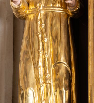 Zdjęcie nr 4: Ołtarz architektoniczny, jednokondygnacyjny, jednoosiowy, ze zwieńczeniem. Ołtarz prostopadłościenny, z drewnianą mensą. Antepedium ujęte profilowaną, polichromowaną ramą zdobioną ornamentyką roślinną. Błękitne pole ujęte jest kwietną bordiurą, pośrodku polichromowana dekoracja w formie inicjałów AS wplecionych w kwiaty białych lilii. Retabulum osadzone na wysokim, zdwojonym cokole, ujęte dwiema parami kolumn, z których zewnętrzne wysunięte do przodu, ustawionych na tle zdwojonych pilastrów. Podpory podtrzymują przerwane, wyłamujące się ponad nimi belkowanie. Zwieńczenie ujęte parą spływów wolutowych i zamknięte nadwieszonym łukiem odcinkowym. Po bokach ujęte przerwanym, wolutowym przyczółkiem. Pola cokołu retabulum zdobią płyciny z wydłużonymi rozetami, pośrodku kompozycja z wici akantu z rozetką. Część środkową retabulum ujmuje para ażurowych uszaków rocaille’owych z motywami rozetek. W partii przerwanego belkowania jest ornament roślinnego z motywem chrząstki, we fryzie rozety. Pole zwieńczenia zdobi stylizowana ornamentyka roślinna, gzyms motyw astragalu. Szczyt w formie ażurowej konchy ujętej po bokach parą wazonów z kwiatami słonecznika. Na przerwanym przyczółku para aniołków w złoconych szatach. Pole części środkowej w kształcie stojącego prostokąta zamkniętego półkolistym łukiem nadwieszonym z uskokami, ujęte profilowaną, złocono-srebrzoną ramą, z przedstawieniem św. Antoniego Padewskiego, na zasuwie obraz św. Franciszka z Asyżu. Retabulum ujmuje para figur niezidentyfikowanych świętych zakonników. W polu zwieńczenia, w owalnej ramie obraz  św. Roberta Bellarmina. Struktura w kolorze ciemnobrązowym, detal architektoniczny i ornamentyka złocone i posrebrzane.