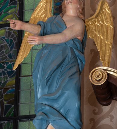 Zdjęcie nr 8: Ołtarz architektoniczny, jednokondygnacyjny, jednoosiowy ze zwieńczeniem i z parą bramek. Ołtarz murowany, prostopadłościenny z malowanym na płótnie antepedium ujętym drewnianą, profilowaną ramą. Wewnątrz przedstawienie wkomponowane w trójprzelotową arkadę z wizerunkiem Jezusa pośrodku i sceną Zwiastowania po bokach. Osadzone na niewysokim cokole tabernakulum jest w formie prostopadłościennej szafki o wypukłej ściance frontowej i narożach artykułowanych skośnie ustawionymi pilastrami wspierającymi wyłamujący się ponad nimi gzyms wieńczący przybierający po środku formę stykających się wolut z motywem konchy. Kwadratowe drzwiczki zamknięte są półkolistym łukiem nadwieszonym. Tabernakulum flankuje para wydatnych spływów wolutowych o krawędziach zdobionych motywem rocaille’owego grzebienia. Struktura jest srebrzona i złocona. Retabulum osadzone na zdwojonym, ukośnie zryzalitowanym cokole z otworami bramek na bokach. Część środkową nastawy ujmują dwie pary kolumn o kapitelach korynckich ustawione na tle pary filarów o kanelowanych trzonach, całość wspiera wyłamujące się ponad nimi przerwane w partii architrawu i fryzu belkowanie z silnie wysuniętym gzymsem. Zwieńczenie w formie przerwanego  przyczółka w kształcie S-kształtnych wolut. Górną partię cokołu zdobią motywy rocaille’ów, natomiast fryz motywy rozet. Pośrodku zwieńczenia usytuowana jest okrągła, promienista gloria z monogramem imienia Jezus i gorejącym sercem pośrodku. Po bokach zwieńczenia stoi para figur aniołów ubranych w niebieskie szaty. Pole środkowe retabulum w formie wnęki w kształcie stojącego prostokąta zamkniętego łukiem koszowym. Wewnątrz krucyfiks na polichromowanym tle przestawiającym widok miasta z murami warownymi i wydatną bryłą kościoła po prawej stronie kompozycji, pokrytym skłębionymi chmurami niebem oraz tarczami - słoneczną po prawej i księżycową po lewej stronie górnej partii krucyfiksu. Struktura ołtarza  jest w kolorze brązowym, detal architektoniczny i ornamentyka są złocone i srebrzone.      