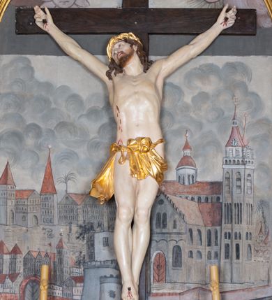 Zdjęcie nr 3: Ołtarz architektoniczny, jednokondygnacyjny, jednoosiowy ze zwieńczeniem i z parą bramek. Ołtarz murowany, prostopadłościenny z malowanym na płótnie antepedium ujętym drewnianą, profilowaną ramą. Wewnątrz przedstawienie wkomponowane w trójprzelotową arkadę z wizerunkiem Jezusa pośrodku i sceną Zwiastowania po bokach. Osadzone na niewysokim cokole tabernakulum jest w formie prostopadłościennej szafki o wypukłej ściance frontowej i narożach artykułowanych skośnie ustawionymi pilastrami wspierającymi wyłamujący się ponad nimi gzyms wieńczący przybierający po środku formę stykających się wolut z motywem konchy. Kwadratowe drzwiczki zamknięte są półkolistym łukiem nadwieszonym. Tabernakulum flankuje para wydatnych spływów wolutowych o krawędziach zdobionych motywem rocaille’owego grzebienia. Struktura jest srebrzona i złocona. Retabulum osadzone na zdwojonym, ukośnie zryzalitowanym cokole z otworami bramek na bokach. Część środkową nastawy ujmują dwie pary kolumn o kapitelach korynckich ustawione na tle pary filarów o kanelowanych trzonach, całość wspiera wyłamujące się ponad nimi przerwane w partii architrawu i fryzu belkowanie z silnie wysuniętym gzymsem. Zwieńczenie w formie przerwanego  przyczółka w kształcie S-kształtnych wolut. Górną partię cokołu zdobią motywy rocaille’ów, natomiast fryz motywy rozet. Pośrodku zwieńczenia usytuowana jest okrągła, promienista gloria z monogramem imienia Jezus i gorejącym sercem pośrodku. Po bokach zwieńczenia stoi para figur aniołów ubranych w niebieskie szaty. Pole środkowe retabulum w formie wnęki w kształcie stojącego prostokąta zamkniętego łukiem koszowym. Wewnątrz krucyfiks na polichromowanym tle przestawiającym widok miasta z murami warownymi i wydatną bryłą kościoła po prawej stronie kompozycji, pokrytym skłębionymi chmurami niebem oraz tarczami - słoneczną po prawej i księżycową po lewej stronie górnej partii krucyfiksu. Struktura ołtarza  jest w kolorze brązowym, detal architektoniczny i ornamentyka są złocone i srebrzone.      