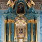 Zdjęcie nr 1: Ołtarz architektoniczny, jednokondygnacyjny, jednoosiowy ze zwieńczeniem. Ołtarz drewniany, prostopadłościenny, ustawiony na dwustopniowej podstawie. Antependium w formie leżącego prostokąta ujętego ramą dekorowaną akantem; w polu owalny medalion w wieńcu z monogramem maryjnym, wkomponowany w gęste wici suchego akantu.
Tabernakulum w formie drewnianej skrzynki na cokole o wklęsło-wypukłym licu, ujęte dwoma parami pilastrów o trzonach utworzonych z podwójnych spływów wolutowych; dźwigających pełne belkowanie opasujące ściankę frontową, wyłamane na osi podpór. Drzwiczki w formie stojącego prostokąta zamkniętego łukiem półkolistym nadwieszonym z krzyżem w polu, na którego przecięciu ramion medalion z monogramem imienia Jezus w glorii. Tron wystawienia w postaci podestu wspartego na pięciu kabłąkach. Struktura w całości srebrzona, podpory i profile złocone.
Nastawa osadzona na zdwojonym cokole, górny lekko wybrzuszony. Część środkowa ujęta parą pilastrów o kanelowanych trzonach i kapitelach kompozytowych zwróconych do wewnątrz lica ołtarza oraz trzema parami analogicznych pilastrów ustawionych pod kątem na zewnątrz przed którymi stoją dwie pary kolumn o kapitelach kompozytowych. Podpory dźwigają pełne belkowanie, przerwane belkowanie o lekko wybrzuszonym fryzie i wklęsłej linii gzymsu. Zwieńczenie ujęte parą spływów wolutowych i zamknięte fragmentem gzymsu w postaci łuku wklęsło-wypukłego. Całość flankuje przerwany, ustawiony skośnie, falisty przyczółek. Pole przerwanego belkowania wypełnia schweifwerk przechodzący w wić roślinną z motywami rozet oraz parą puttów podtrzymujących koronę. Spływy wolutowe zwieńczenia zdobią kampanule, oraz para wazonów, gzyms wieńczący zaś trzy konchy. Na przerwanym przyczółku para figur klęczących aniołów.  Pole części środkowej retabulum w formie głębokiej niszy w kształcie stojącego prostokąta zamkniętego łukiem odcinkowym łukiem nadwieszonym z uskokami, ujętej profilowaną ramą, we wnątrz znajduje się obraz Matki Boskiej Myślenickiej. W zwieńczeniu obraz w kształcie trapezu o wklęsłych ramionach, podstawie i narożach zamknięty łukiem wklęsło-wypukłym, ujęty profilowaną ramą, z wizerunkiem św. Tekli. 
Struktura w całości marmoryzowana w kolorze zielono-granatowym; kolumny, ornamentyka i profile złocone i srebrzone.
