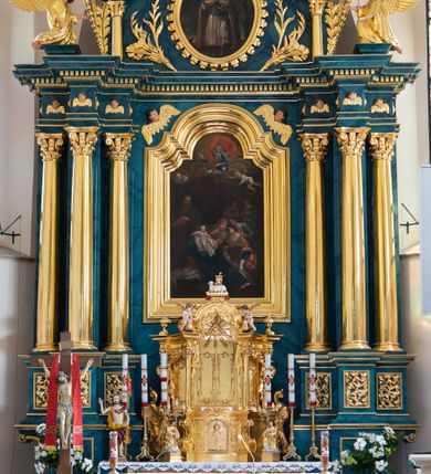 Zdjęcie nr 2: Ołtarz przyścienny, jednokondygnacyjny, jednoosiowy, ze zwieńczeniem. Ołtarz prostopadłościenny, tabernakulum z tronem wystawienia w formie architektonicznej na rzucie trapezoidalnym. W przedniej ściance wysokiego cokołu, o narożach ujętych spływami wolutowymi, są drzwiczki w kształcie prostokąta zamkniętego półkolistym łukiem nadwieszonym zdobione płaskorzeźbionym przedstawieniem kielicha eucharystycznego. Cokół wieńczy gzyms przekształcający się pośrodku w parę stykających się wolut. Na występach nad spływami cokołu osadzone kolumienki wspierające wyłamujące się ponad nimi belkowanie baldachimu tronu wystawienia. Zwieńczenie w formie pary stykających się spływów wolutowych z motywem paludamentu. Zaplecek zdobiony płycinami z ornamentalnymi obramieniami z motywami rocaille’u, w górnej partii płaskorzeźbiony trójkąt z okiem Opatrzności Bożej ujęty promienistą glorią. W zwieńczeniu para wazonów i para figurek aniołków, na szczycie księga z siedmioma pieczęciami i leżącym barankiem paschalnym.  
Retabulum osadzone na zdwojonym cokole, w górnej partii o zryzalitowanych bokach. Część środkową ujmują trzy pary kolumn, z których środkowe wysunięte, wspierających przerwane w partii architrawu i fryzu belkowanie. Zwieńczenie ujęte parą kolumn wspierających gzyms w formie trójkątnego przyczółka. Pola cokołu retabulum wypełnia stylizowana ornamentyka roślinna, partie fryzu oraz górne naroża części środkowej zdobią uskrzydlone główki anielskie, a gzyms kostkowanie. Zwieńczenie ujęte po bokach motywem liści paproci, pole ulistnionymi gałązkami z wstążką. Krawędź gzymsu wieńczącego zdobi wić roślinna z krzyżem pośrodku, po bokach para wazonów. Całość ujmuje para figur klęczących aniołów. Pole części środkowej w kształcie stojącego prostokąta ujętego profilowaną, złoconą ramą z przedstawieniem Narodzenia Najświętszej Marii Panny. W zwieńczeniu obraz w kształcie stojącego owalu, ujętego ramą zdobioną akantowymi liśćmi, z wizerunkiem św. Mikołaja. Struktura marmoryzowana w odcieniach błękitów, detal architektoniczny i ornamentyka złocone.   
