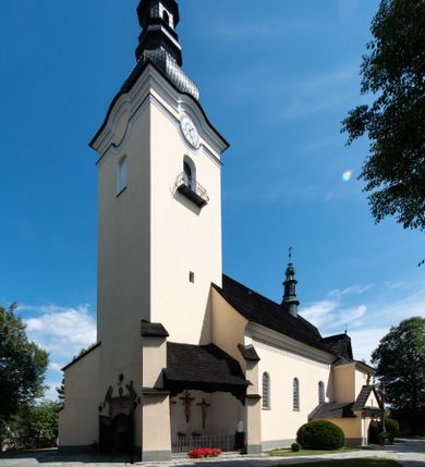 Zdjęcie nr 1: Świątynia otoczona jest murem kamiennym, tynkowanym, nakrytym daszkiem gontowym, jednospadowym. Wejścia znajdują się w murze od strony południowej. Pierwsze, prowadzące do głównych drzwi jest kamienną, późnobarokową bramką z herbem księdza Józefa Sawickiego, datą „1765” oraz figurą św. Jana Kantego. Drugie wejście prowadzi przez dzwonnicę. W murze, od strony wewnętrznej jest 14 wnęk po stacjach drogi krzyżowej. Teren wokół świątyni jest starym cmentarzem, bez zachowanych nagrobków.

Kościół jest budowlą założoną na planie prostokąta, orientowaną, jednonawową z ramionami w rodzaju krótkiego transeptu z wieżą od zachodu, zakrystią i kaplicą od północy oraz kruchtą od południa. Prezbiterium zamknięte jest wielobocznie, trójprzęsłowe, węższe i niższe od nawy. Nawa czteroprzęsłowa, nie jest ulokowana na jednej osi z prezbiterium. 

Artykulacja ścian jest przeprowadzona za pomocą pilastrów toskańskich podtrzymujących sklepienie kolebkowe z lunetami. Ramiona transeptu, kaplica Matki Boskiej Różańcowej oraz kruchta są sklepione krzyżowo. Otwory okienne: w prezbiterium cztery, w nawie cztery od południa, wszystkie zamknięte łukami półkolistymi. Zakrystia piętrowa z jednym oknem na parterze i dwoma na piętrze; od strony północnej kaplica Matki Boskiej Różańcowej z dwoma oknami i jedną, zamurowaną wnęką; obok mała zakrystia. Z prezbiterium do zakrystii prowadzi portal kamienny z inicjałami, herbem i portretem księdza Sawickiego. Na arkadzie tęczowej od strony nawy nowy napis: „FUNDATA A CASIMIRO MAGNO ANNO DOM[INI] 1346”. W pierwszym od strony fasady przęśle znajduje się drewniany chór muzyczny, wsparty na dwóch filarach.

Fasada zachodnia kościoła jest płaska z wieżą, nakryta kopułą z latarnią. Na narożnikach zewnętrznych wieży i naw oraz przy absydzie szkarpy, kryte daszkiem gontowym. Na frontowej ścianie wieży kamienny portal, nad nim sygle „I(osephus) S(awicki) / 1765” oraz herb Nowina. Od strony zachodniej wieża, ozdobiona półkolistymi blendami. Od strony południowej balkonik otoczony żelazną kratą z napisem „1343-1943”. Nad balkonikiem umieszczona jest tarcza zegara, taka sama widnieje od strony północnej, a od zachodniej i wschodniej odpowiadają im tarcze w murze. Przy wieży, od strony północnej wieżyczka w kształcie walca, ścięta od połowy, nakryta daszkiem stożkowym. Przy południowej ścianie wieży między dwiema szkarpami znajduje się kapliczka Ukrzyżowania z figurami Chrystusa Ukrzyżowanego i dwóch łotrów na krzyżach. Dach kościoła siodłowy, kryty gontem.

Na zewnętrznej, południowej ścianie napis: „AEDIFICATA H(A)EC EC[C]LESIA / A[NNO] D[OMINI] / 1606 / PETRVS CZARNY MVLARS”. Niżej wmurowana w półokrągłą wnękę z piaskowca figura Matki Boskiej Niepokalanie Poczętej. Po lewej stronie, u góry fragment fryzu dekoracyjnego, malowany w kolorze czerwonym o motywie zwisających esownic ze stylizowanymi kwiatami i liliami. 

Dzwonnica na planie kwadratu, murowana, otynkowana, dwupiętrowa z sienią przejściową sklepioną, ujętą na zaokrąglonych narożnikach zdwojonymi pilastrami; nakryta gontowym hełmem. Na osi dzwonnicy portal bramy flankowany dwoma pilastrami, o spłaszczonej archiwolcie. Nad belkowaniem monogram maryjny i data „1701”. W sieni na ścianie wschodniej barokowy krucyfiks oraz rzeźby Matki Boskiej i św. Jana Ewangelisty, na ścianie pozostałości polichromii z XVIII wieku.
