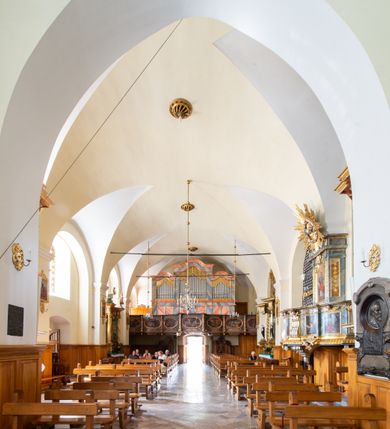Zdjęcie nr 19: Świątynia otoczona jest murem kamiennym, tynkowanym, nakrytym daszkiem gontowym, jednospadowym. Wejścia znajdują się w murze od strony południowej. Pierwsze, prowadzące do głównych drzwi jest kamienną, późnobarokową bramką z herbem księdza Józefa Sawickiego, datą „1765” oraz figurą św. Jana Kantego. Drugie wejście prowadzi przez dzwonnicę. W murze, od strony wewnętrznej jest 14 wnęk po stacjach drogi krzyżowej. Teren wokół świątyni jest starym cmentarzem, bez zachowanych nagrobków.

Kościół jest budowlą założoną na planie prostokąta, orientowaną, jednonawową z ramionami w rodzaju krótkiego transeptu z wieżą od zachodu, zakrystią i kaplicą od północy oraz kruchtą od południa. Prezbiterium zamknięte jest wielobocznie, trójprzęsłowe, węższe i niższe od nawy. Nawa czteroprzęsłowa, nie jest ulokowana na jednej osi z prezbiterium. 

Artykulacja ścian jest przeprowadzona za pomocą pilastrów toskańskich podtrzymujących sklepienie kolebkowe z lunetami. Ramiona transeptu, kaplica Matki Boskiej Różańcowej oraz kruchta są sklepione krzyżowo. Otwory okienne: w prezbiterium cztery, w nawie cztery od południa, wszystkie zamknięte łukami półkolistymi. Zakrystia piętrowa z jednym oknem na parterze i dwoma na piętrze; od strony północnej kaplica Matki Boskiej Różańcowej z dwoma oknami i jedną, zamurowaną wnęką; obok mała zakrystia. Z prezbiterium do zakrystii prowadzi portal kamienny z inicjałami, herbem i portretem księdza Sawickiego. Na arkadzie tęczowej od strony nawy nowy napis: „FUNDATA A CASIMIRO MAGNO ANNO DOM[INI] 1346”. W pierwszym od strony fasady przęśle znajduje się drewniany chór muzyczny, wsparty na dwóch filarach.

Fasada zachodnia kościoła jest płaska z wieżą, nakryta kopułą z latarnią. Na narożnikach zewnętrznych wieży i naw oraz przy absydzie szkarpy, kryte daszkiem gontowym. Na frontowej ścianie wieży kamienny portal, nad nim sygle „I(osephus) S(awicki) / 1765” oraz herb Nowina. Od strony zachodniej wieża, ozdobiona półkolistymi blendami. Od strony południowej balkonik otoczony żelazną kratą z napisem „1343-1943”. Nad balkonikiem umieszczona jest tarcza zegara, taka sama widnieje od strony północnej, a od zachodniej i wschodniej odpowiadają im tarcze w murze. Przy wieży, od strony północnej wieżyczka w kształcie walca, ścięta od połowy, nakryta daszkiem stożkowym. Przy południowej ścianie wieży między dwiema szkarpami znajduje się kapliczka Ukrzyżowania z figurami Chrystusa Ukrzyżowanego i dwóch łotrów na krzyżach. Dach kościoła siodłowy, kryty gontem.

Na zewnętrznej, południowej ścianie napis: „AEDIFICATA H(A)EC EC[C]LESIA / A[NNO] D[OMINI] / 1606 / PETRVS CZARNY MVLARS”. Niżej wmurowana w półokrągłą wnękę z piaskowca figura Matki Boskiej Niepokalanie Poczętej. Po lewej stronie, u góry fragment fryzu dekoracyjnego, malowany w kolorze czerwonym o motywie zwisających esownic ze stylizowanymi kwiatami i liliami. 

Dzwonnica na planie kwadratu, murowana, otynkowana, dwupiętrowa z sienią przejściową sklepioną, ujętą na zaokrąglonych narożnikach zdwojonymi pilastrami; nakryta gontowym hełmem. Na osi dzwonnicy portal bramy flankowany dwoma pilastrami, o spłaszczonej archiwolcie. Nad belkowaniem monogram maryjny i data „1701”. W sieni na ścianie wschodniej barokowy krucyfiks oraz rzeźby Matki Boskiej i św. Jana Ewangelisty, na ścianie pozostałości polichromii z XVIII wieku.
