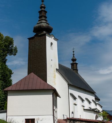 Zdjęcie nr 38: Kościół św. Piotra i św. Pawła jest usytuowany w centrum Łapsz Wyżnych, na południe od głównej drogi z Trybsza do Łapsz Niżnych. Teren przykościelny jest otoczony wysokim kamiennym i częściowo otynkowanym murem, nakrytym gontem od strony wschodniej, zachodniej i północnej oraz nakrytym blachą od strony południowej; daszki jednospadowe, nachylone na zewnątrz. W części zachodniej muru zlokalizowana jest szeroka brama, flankowana dwoma masywnymi filarami, na których ustawione są okrągłe słupy, przykryte stożkowym daszkiem gontowym i zwieńczone krzyżykami. Od wschodu analogiczne wejście z szerszym przejściem, dostępnym schodkami. Trzecie wejście na teren przykościelny prowadzi od północy przez bramę w kształcie arkady zamkniętej łukiem odcinkowym, zwieńczonej trójkątnym nadprożem, na którego szczycie ustawiony jest krzyż i wazony po bokach. Czwarte wejście zlokalizowane w zachodnio-południowym narożniku muru prowadzi przez wysokie schody z balustradą. Od zachodu w ogrodzeniu ulokowany jest budynek salki katechetycznej (dawna kostnica) wchodzącej w mur ścianą frontową. W obrębie placu przykościelnego znajdują się resztki cmentarza w postaci kamiennych i granitowych nagrobków oraz żeliwnych krzyży. 

Kościół jest orientowany, murowany, otynkowany, jednonawowy z czworoboczną wieżą w fasadzie z prezbiterium zamkniętym półkoliście. Dwuprzęsłowe prezbiterium oddziela od nawy ściana arkady tęczowej. Nawa jest szersza, trójprzęsłowa. Wnętrze artykułowane pilastrami wspierającymi sklepienie kolebkowe z lunetami na gurtach, ozdobione stiukowymi, późnobarokowymi ramami. Od południa do prezbiterium przylega zakrystia na planie prostokąta, a do nawy od północny kruchta z portalem z zaakcentowaną datą: „1760”. Na zachodniej ścianie nawy chór muzyczny wsparty jest na trzech półkolistych arkadach. 

Wnętrze oświetlają umieszczone w południowych i północnych ścianach nawy prostokątne, zamknięte półkoliście cztery okna, takie same dwa znajdują się w prezbiterium; w wieży trzy podobne okna umieszczone po jednym z każdej strony, oprócz ściany zachodniej; w apsydzie jedno małe, okrągłe okno. Do kościoła prowadzi główne wejście od strony zachodniej oraz dwa mniejsze od strony północnej przez kruchtę i od strony południowej przez zakrystię.

W zewnętrznej elewacji kościoła widoczny jest niewysoki, kamienny cokół, powyżej kościół jest otynkowany. Prezbiterium, niższe od nawy. Nawa oszkarpowana, nakryta dachem dwuspadowym z wieżą na sygnaturkę na skrzyżowaniu na wschodnim zakończeniu nawy. Do zachodniej fasady kościoła dostawiona jest wysoka założona na planie kwadratu wieża-dzwonnica. W dolnej kondygnacji na osi kościoła znajduje się prostokątne wejście do kruchty, zamknięte półkoliście. Fasada wieży w całości pokryta jest blachą, przechodzącą nad głównym wejściem do kościoła w daszek. Hełm wieży baniasty z latarnią.
