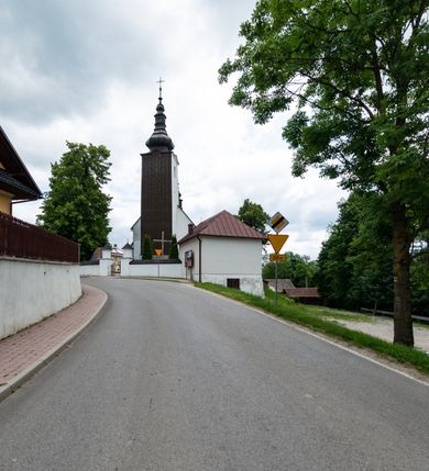 Zdjęcie nr 13: Kościół św. Piotra i św. Pawła jest usytuowany w centrum Łapsz Wyżnych, na południe od głównej drogi z Trybsza do Łapsz Niżnych. Teren przykościelny jest otoczony wysokim kamiennym i częściowo otynkowanym murem, nakrytym gontem od strony wschodniej, zachodniej i północnej oraz nakrytym blachą od strony południowej; daszki jednospadowe, nachylone na zewnątrz. W części zachodniej muru zlokalizowana jest szeroka brama, flankowana dwoma masywnymi filarami, na których ustawione są okrągłe słupy, przykryte stożkowym daszkiem gontowym i zwieńczone krzyżykami. Od wschodu analogiczne wejście z szerszym przejściem, dostępnym schodkami. Trzecie wejście na teren przykościelny prowadzi od północy przez bramę w kształcie arkady zamkniętej łukiem odcinkowym, zwieńczonej trójkątnym nadprożem, na którego szczycie ustawiony jest krzyż i wazony po bokach. Czwarte wejście zlokalizowane w zachodnio-południowym narożniku muru prowadzi przez wysokie schody z balustradą. Od zachodu w ogrodzeniu ulokowany jest budynek salki katechetycznej (dawna kostnica) wchodzącej w mur ścianą frontową. W obrębie placu przykościelnego znajdują się resztki cmentarza w postaci kamiennych i granitowych nagrobków oraz żeliwnych krzyży. 

Kościół jest orientowany, murowany, otynkowany, jednonawowy z czworoboczną wieżą w fasadzie z prezbiterium zamkniętym półkoliście. Dwuprzęsłowe prezbiterium oddziela od nawy ściana arkady tęczowej. Nawa jest szersza, trójprzęsłowa. Wnętrze artykułowane pilastrami wspierającymi sklepienie kolebkowe z lunetami na gurtach, ozdobione stiukowymi, późnobarokowymi ramami. Od południa do prezbiterium przylega zakrystia na planie prostokąta, a do nawy od północny kruchta z portalem z zaakcentowaną datą: „1760”. Na zachodniej ścianie nawy chór muzyczny wsparty jest na trzech półkolistych arkadach. 

Wnętrze oświetlają umieszczone w południowych i północnych ścianach nawy prostokątne, zamknięte półkoliście cztery okna, takie same dwa znajdują się w prezbiterium; w wieży trzy podobne okna umieszczone po jednym z każdej strony, oprócz ściany zachodniej; w apsydzie jedno małe, okrągłe okno. Do kościoła prowadzi główne wejście od strony zachodniej oraz dwa mniejsze od strony północnej przez kruchtę i od strony południowej przez zakrystię.

W zewnętrznej elewacji kościoła widoczny jest niewysoki, kamienny cokół, powyżej kościół jest otynkowany. Prezbiterium, niższe od nawy. Nawa oszkarpowana, nakryta dachem dwuspadowym z wieżą na sygnaturkę na skrzyżowaniu na wschodnim zakończeniu nawy. Do zachodniej fasady kościoła dostawiona jest wysoka założona na planie kwadratu wieża-dzwonnica. W dolnej kondygnacji na osi kościoła znajduje się prostokątne wejście do kruchty, zamknięte półkoliście. Fasada wieży w całości pokryta jest blachą, przechodzącą nad głównym wejściem do kościoła w daszek. Hełm wieży baniasty z latarnią.
