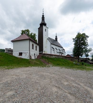 Zdjęcie nr 34: Kościół św. Piotra i św. Pawła jest usytuowany w centrum Łapsz Wyżnych, na południe od głównej drogi z Trybsza do Łapsz Niżnych. Teren przykościelny jest otoczony wysokim kamiennym i częściowo otynkowanym murem, nakrytym gontem od strony wschodniej, zachodniej i północnej oraz nakrytym blachą od strony południowej; daszki jednospadowe, nachylone na zewnątrz. W części zachodniej muru zlokalizowana jest szeroka brama, flankowana dwoma masywnymi filarami, na których ustawione są okrągłe słupy, przykryte stożkowym daszkiem gontowym i zwieńczone krzyżykami. Od wschodu analogiczne wejście z szerszym przejściem, dostępnym schodkami. Trzecie wejście na teren przykościelny prowadzi od północy przez bramę w kształcie arkady zamkniętej łukiem odcinkowym, zwieńczonej trójkątnym nadprożem, na którego szczycie ustawiony jest krzyż i wazony po bokach. Czwarte wejście zlokalizowane w zachodnio-południowym narożniku muru prowadzi przez wysokie schody z balustradą. Od zachodu w ogrodzeniu ulokowany jest budynek salki katechetycznej (dawna kostnica) wchodzącej w mur ścianą frontową. W obrębie placu przykościelnego znajdują się resztki cmentarza w postaci kamiennych i granitowych nagrobków oraz żeliwnych krzyży. 

Kościół jest orientowany, murowany, otynkowany, jednonawowy z czworoboczną wieżą w fasadzie z prezbiterium zamkniętym półkoliście. Dwuprzęsłowe prezbiterium oddziela od nawy ściana arkady tęczowej. Nawa jest szersza, trójprzęsłowa. Wnętrze artykułowane pilastrami wspierającymi sklepienie kolebkowe z lunetami na gurtach, ozdobione stiukowymi, późnobarokowymi ramami. Od południa do prezbiterium przylega zakrystia na planie prostokąta, a do nawy od północny kruchta z portalem z zaakcentowaną datą: „1760”. Na zachodniej ścianie nawy chór muzyczny wsparty jest na trzech półkolistych arkadach. 

Wnętrze oświetlają umieszczone w południowych i północnych ścianach nawy prostokątne, zamknięte półkoliście cztery okna, takie same dwa znajdują się w prezbiterium; w wieży trzy podobne okna umieszczone po jednym z każdej strony, oprócz ściany zachodniej; w apsydzie jedno małe, okrągłe okno. Do kościoła prowadzi główne wejście od strony zachodniej oraz dwa mniejsze od strony północnej przez kruchtę i od strony południowej przez zakrystię.

W zewnętrznej elewacji kościoła widoczny jest niewysoki, kamienny cokół, powyżej kościół jest otynkowany. Prezbiterium, niższe od nawy. Nawa oszkarpowana, nakryta dachem dwuspadowym z wieżą na sygnaturkę na skrzyżowaniu na wschodnim zakończeniu nawy. Do zachodniej fasady kościoła dostawiona jest wysoka założona na planie kwadratu wieża-dzwonnica. W dolnej kondygnacji na osi kościoła znajduje się prostokątne wejście do kruchty, zamknięte półkoliście. Fasada wieży w całości pokryta jest blachą, przechodzącą nad głównym wejściem do kościoła w daszek. Hełm wieży baniasty z latarnią.
