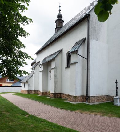 Zdjęcie nr 8: Kościół św. Piotra i św. Pawła jest usytuowany w centrum Łapsz Wyżnych, na południe od głównej drogi z Trybsza do Łapsz Niżnych. Teren przykościelny jest otoczony wysokim kamiennym i częściowo otynkowanym murem, nakrytym gontem od strony wschodniej, zachodniej i północnej oraz nakrytym blachą od strony południowej; daszki jednospadowe, nachylone na zewnątrz. W części zachodniej muru zlokalizowana jest szeroka brama, flankowana dwoma masywnymi filarami, na których ustawione są okrągłe słupy, przykryte stożkowym daszkiem gontowym i zwieńczone krzyżykami. Od wschodu analogiczne wejście z szerszym przejściem, dostępnym schodkami. Trzecie wejście na teren przykościelny prowadzi od północy przez bramę w kształcie arkady zamkniętej łukiem odcinkowym, zwieńczonej trójkątnym nadprożem, na którego szczycie ustawiony jest krzyż i wazony po bokach. Czwarte wejście zlokalizowane w zachodnio-południowym narożniku muru prowadzi przez wysokie schody z balustradą. Od zachodu w ogrodzeniu ulokowany jest budynek salki katechetycznej (dawna kostnica) wchodzącej w mur ścianą frontową. W obrębie placu przykościelnego znajdują się resztki cmentarza w postaci kamiennych i granitowych nagrobków oraz żeliwnych krzyży. 

Kościół jest orientowany, murowany, otynkowany, jednonawowy z czworoboczną wieżą w fasadzie z prezbiterium zamkniętym półkoliście. Dwuprzęsłowe prezbiterium oddziela od nawy ściana arkady tęczowej. Nawa jest szersza, trójprzęsłowa. Wnętrze artykułowane pilastrami wspierającymi sklepienie kolebkowe z lunetami na gurtach, ozdobione stiukowymi, późnobarokowymi ramami. Od południa do prezbiterium przylega zakrystia na planie prostokąta, a do nawy od północny kruchta z portalem z zaakcentowaną datą: „1760”. Na zachodniej ścianie nawy chór muzyczny wsparty jest na trzech półkolistych arkadach. 

Wnętrze oświetlają umieszczone w południowych i północnych ścianach nawy prostokątne, zamknięte półkoliście cztery okna, takie same dwa znajdują się w prezbiterium; w wieży trzy podobne okna umieszczone po jednym z każdej strony, oprócz ściany zachodniej; w apsydzie jedno małe, okrągłe okno. Do kościoła prowadzi główne wejście od strony zachodniej oraz dwa mniejsze od strony północnej przez kruchtę i od strony południowej przez zakrystię.

W zewnętrznej elewacji kościoła widoczny jest niewysoki, kamienny cokół, powyżej kościół jest otynkowany. Prezbiterium, niższe od nawy. Nawa oszkarpowana, nakryta dachem dwuspadowym z wieżą na sygnaturkę na skrzyżowaniu na wschodnim zakończeniu nawy. Do zachodniej fasady kościoła dostawiona jest wysoka założona na planie kwadratu wieża-dzwonnica. W dolnej kondygnacji na osi kościoła znajduje się prostokątne wejście do kruchty, zamknięte półkoliście. Fasada wieży w całości pokryta jest blachą, przechodzącą nad głównym wejściem do kościoła w daszek. Hełm wieży baniasty z latarnią.
