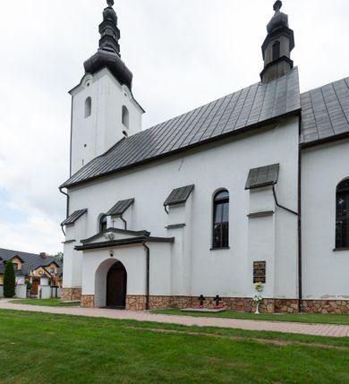 Zdjęcie nr 11: Kościół św. Piotra i św. Pawła jest usytuowany w centrum Łapsz Wyżnych, na południe od głównej drogi z Trybsza do Łapsz Niżnych. Teren przykościelny jest otoczony wysokim kamiennym i częściowo otynkowanym murem, nakrytym gontem od strony wschodniej, zachodniej i północnej oraz nakrytym blachą od strony południowej; daszki jednospadowe, nachylone na zewnątrz. W części zachodniej muru zlokalizowana jest szeroka brama, flankowana dwoma masywnymi filarami, na których ustawione są okrągłe słupy, przykryte stożkowym daszkiem gontowym i zwieńczone krzyżykami. Od wschodu analogiczne wejście z szerszym przejściem, dostępnym schodkami. Trzecie wejście na teren przykościelny prowadzi od północy przez bramę w kształcie arkady zamkniętej łukiem odcinkowym, zwieńczonej trójkątnym nadprożem, na którego szczycie ustawiony jest krzyż i wazony po bokach. Czwarte wejście zlokalizowane w zachodnio-południowym narożniku muru prowadzi przez wysokie schody z balustradą. Od zachodu w ogrodzeniu ulokowany jest budynek salki katechetycznej (dawna kostnica) wchodzącej w mur ścianą frontową. W obrębie placu przykościelnego znajdują się resztki cmentarza w postaci kamiennych i granitowych nagrobków oraz żeliwnych krzyży. 

Kościół jest orientowany, murowany, otynkowany, jednonawowy z czworoboczną wieżą w fasadzie z prezbiterium zamkniętym półkoliście. Dwuprzęsłowe prezbiterium oddziela od nawy ściana arkady tęczowej. Nawa jest szersza, trójprzęsłowa. Wnętrze artykułowane pilastrami wspierającymi sklepienie kolebkowe z lunetami na gurtach, ozdobione stiukowymi, późnobarokowymi ramami. Od południa do prezbiterium przylega zakrystia na planie prostokąta, a do nawy od północny kruchta z portalem z zaakcentowaną datą: „1760”. Na zachodniej ścianie nawy chór muzyczny wsparty jest na trzech półkolistych arkadach. 

Wnętrze oświetlają umieszczone w południowych i północnych ścianach nawy prostokątne, zamknięte półkoliście cztery okna, takie same dwa znajdują się w prezbiterium; w wieży trzy podobne okna umieszczone po jednym z każdej strony, oprócz ściany zachodniej; w apsydzie jedno małe, okrągłe okno. Do kościoła prowadzi główne wejście od strony zachodniej oraz dwa mniejsze od strony północnej przez kruchtę i od strony południowej przez zakrystię.

W zewnętrznej elewacji kościoła widoczny jest niewysoki, kamienny cokół, powyżej kościół jest otynkowany. Prezbiterium, niższe od nawy. Nawa oszkarpowana, nakryta dachem dwuspadowym z wieżą na sygnaturkę na skrzyżowaniu na wschodnim zakończeniu nawy. Do zachodniej fasady kościoła dostawiona jest wysoka założona na planie kwadratu wieża-dzwonnica. W dolnej kondygnacji na osi kościoła znajduje się prostokątne wejście do kruchty, zamknięte półkoliście. Fasada wieży w całości pokryta jest blachą, przechodzącą nad głównym wejściem do kościoła w daszek. Hełm wieży baniasty z latarnią.
