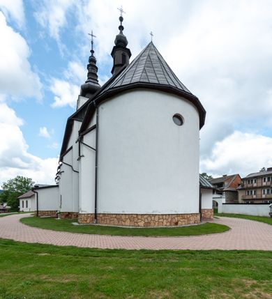 Zdjęcie nr 22: Kościół św. Piotra i św. Pawła jest usytuowany w centrum Łapsz Wyżnych, na południe od głównej drogi z Trybsza do Łapsz Niżnych. Teren przykościelny jest otoczony wysokim kamiennym i częściowo otynkowanym murem, nakrytym gontem od strony wschodniej, zachodniej i północnej oraz nakrytym blachą od strony południowej; daszki jednospadowe, nachylone na zewnątrz. W części zachodniej muru zlokalizowana jest szeroka brama, flankowana dwoma masywnymi filarami, na których ustawione są okrągłe słupy, przykryte stożkowym daszkiem gontowym i zwieńczone krzyżykami. Od wschodu analogiczne wejście z szerszym przejściem, dostępnym schodkami. Trzecie wejście na teren przykościelny prowadzi od północy przez bramę w kształcie arkady zamkniętej łukiem odcinkowym, zwieńczonej trójkątnym nadprożem, na którego szczycie ustawiony jest krzyż i wazony po bokach. Czwarte wejście zlokalizowane w zachodnio-południowym narożniku muru prowadzi przez wysokie schody z balustradą. Od zachodu w ogrodzeniu ulokowany jest budynek salki katechetycznej (dawna kostnica) wchodzącej w mur ścianą frontową. W obrębie placu przykościelnego znajdują się resztki cmentarza w postaci kamiennych i granitowych nagrobków oraz żeliwnych krzyży. 

Kościół jest orientowany, murowany, otynkowany, jednonawowy z czworoboczną wieżą w fasadzie z prezbiterium zamkniętym półkoliście. Dwuprzęsłowe prezbiterium oddziela od nawy ściana arkady tęczowej. Nawa jest szersza, trójprzęsłowa. Wnętrze artykułowane pilastrami wspierającymi sklepienie kolebkowe z lunetami na gurtach, ozdobione stiukowymi, późnobarokowymi ramami. Od południa do prezbiterium przylega zakrystia na planie prostokąta, a do nawy od północny kruchta z portalem z zaakcentowaną datą: „1760”. Na zachodniej ścianie nawy chór muzyczny wsparty jest na trzech półkolistych arkadach. 

Wnętrze oświetlają umieszczone w południowych i północnych ścianach nawy prostokątne, zamknięte półkoliście cztery okna, takie same dwa znajdują się w prezbiterium; w wieży trzy podobne okna umieszczone po jednym z każdej strony, oprócz ściany zachodniej; w apsydzie jedno małe, okrągłe okno. Do kościoła prowadzi główne wejście od strony zachodniej oraz dwa mniejsze od strony północnej przez kruchtę i od strony południowej przez zakrystię.

W zewnętrznej elewacji kościoła widoczny jest niewysoki, kamienny cokół, powyżej kościół jest otynkowany. Prezbiterium, niższe od nawy. Nawa oszkarpowana, nakryta dachem dwuspadowym z wieżą na sygnaturkę na skrzyżowaniu na wschodnim zakończeniu nawy. Do zachodniej fasady kościoła dostawiona jest wysoka założona na planie kwadratu wieża-dzwonnica. W dolnej kondygnacji na osi kościoła znajduje się prostokątne wejście do kruchty, zamknięte półkoliście. Fasada wieży w całości pokryta jest blachą, przechodzącą nad głównym wejściem do kościoła w daszek. Hełm wieży baniasty z latarnią.
