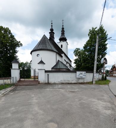 Zdjęcie nr 18: Kościół św. Piotra i św. Pawła jest usytuowany w centrum Łapsz Wyżnych, na południe od głównej drogi z Trybsza do Łapsz Niżnych. Teren przykościelny jest otoczony wysokim kamiennym i częściowo otynkowanym murem, nakrytym gontem od strony wschodniej, zachodniej i północnej oraz nakrytym blachą od strony południowej; daszki jednospadowe, nachylone na zewnątrz. W części zachodniej muru zlokalizowana jest szeroka brama, flankowana dwoma masywnymi filarami, na których ustawione są okrągłe słupy, przykryte stożkowym daszkiem gontowym i zwieńczone krzyżykami. Od wschodu analogiczne wejście z szerszym przejściem, dostępnym schodkami. Trzecie wejście na teren przykościelny prowadzi od północy przez bramę w kształcie arkady zamkniętej łukiem odcinkowym, zwieńczonej trójkątnym nadprożem, na którego szczycie ustawiony jest krzyż i wazony po bokach. Czwarte wejście zlokalizowane w zachodnio-południowym narożniku muru prowadzi przez wysokie schody z balustradą. Od zachodu w ogrodzeniu ulokowany jest budynek salki katechetycznej (dawna kostnica) wchodzącej w mur ścianą frontową. W obrębie placu przykościelnego znajdują się resztki cmentarza w postaci kamiennych i granitowych nagrobków oraz żeliwnych krzyży. 

Kościół jest orientowany, murowany, otynkowany, jednonawowy z czworoboczną wieżą w fasadzie z prezbiterium zamkniętym półkoliście. Dwuprzęsłowe prezbiterium oddziela od nawy ściana arkady tęczowej. Nawa jest szersza, trójprzęsłowa. Wnętrze artykułowane pilastrami wspierającymi sklepienie kolebkowe z lunetami na gurtach, ozdobione stiukowymi, późnobarokowymi ramami. Od południa do prezbiterium przylega zakrystia na planie prostokąta, a do nawy od północny kruchta z portalem z zaakcentowaną datą: „1760”. Na zachodniej ścianie nawy chór muzyczny wsparty jest na trzech półkolistych arkadach. 

Wnętrze oświetlają umieszczone w południowych i północnych ścianach nawy prostokątne, zamknięte półkoliście cztery okna, takie same dwa znajdują się w prezbiterium; w wieży trzy podobne okna umieszczone po jednym z każdej strony, oprócz ściany zachodniej; w apsydzie jedno małe, okrągłe okno. Do kościoła prowadzi główne wejście od strony zachodniej oraz dwa mniejsze od strony północnej przez kruchtę i od strony południowej przez zakrystię.

W zewnętrznej elewacji kościoła widoczny jest niewysoki, kamienny cokół, powyżej kościół jest otynkowany. Prezbiterium, niższe od nawy. Nawa oszkarpowana, nakryta dachem dwuspadowym z wieżą na sygnaturkę na skrzyżowaniu na wschodnim zakończeniu nawy. Do zachodniej fasady kościoła dostawiona jest wysoka założona na planie kwadratu wieża-dzwonnica. W dolnej kondygnacji na osi kościoła znajduje się prostokątne wejście do kruchty, zamknięte półkoliście. Fasada wieży w całości pokryta jest blachą, przechodzącą nad głównym wejściem do kościoła w daszek. Hełm wieży baniasty z latarnią.
