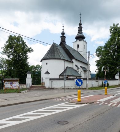 Zdjęcie nr 17: Kościół św. Piotra i św. Pawła jest usytuowany w centrum Łapsz Wyżnych, na południe od głównej drogi z Trybsza do Łapsz Niżnych. Teren przykościelny jest otoczony wysokim kamiennym i częściowo otynkowanym murem, nakrytym gontem od strony wschodniej, zachodniej i północnej oraz nakrytym blachą od strony południowej; daszki jednospadowe, nachylone na zewnątrz. W części zachodniej muru zlokalizowana jest szeroka brama, flankowana dwoma masywnymi filarami, na których ustawione są okrągłe słupy, przykryte stożkowym daszkiem gontowym i zwieńczone krzyżykami. Od wschodu analogiczne wejście z szerszym przejściem, dostępnym schodkami. Trzecie wejście na teren przykościelny prowadzi od północy przez bramę w kształcie arkady zamkniętej łukiem odcinkowym, zwieńczonej trójkątnym nadprożem, na którego szczycie ustawiony jest krzyż i wazony po bokach. Czwarte wejście zlokalizowane w zachodnio-południowym narożniku muru prowadzi przez wysokie schody z balustradą. Od zachodu w ogrodzeniu ulokowany jest budynek salki katechetycznej (dawna kostnica) wchodzącej w mur ścianą frontową. W obrębie placu przykościelnego znajdują się resztki cmentarza w postaci kamiennych i granitowych nagrobków oraz żeliwnych krzyży. 

Kościół jest orientowany, murowany, otynkowany, jednonawowy z czworoboczną wieżą w fasadzie z prezbiterium zamkniętym półkoliście. Dwuprzęsłowe prezbiterium oddziela od nawy ściana arkady tęczowej. Nawa jest szersza, trójprzęsłowa. Wnętrze artykułowane pilastrami wspierającymi sklepienie kolebkowe z lunetami na gurtach, ozdobione stiukowymi, późnobarokowymi ramami. Od południa do prezbiterium przylega zakrystia na planie prostokąta, a do nawy od północny kruchta z portalem z zaakcentowaną datą: „1760”. Na zachodniej ścianie nawy chór muzyczny wsparty jest na trzech półkolistych arkadach. 

Wnętrze oświetlają umieszczone w południowych i północnych ścianach nawy prostokątne, zamknięte półkoliście cztery okna, takie same dwa znajdują się w prezbiterium; w wieży trzy podobne okna umieszczone po jednym z każdej strony, oprócz ściany zachodniej; w apsydzie jedno małe, okrągłe okno. Do kościoła prowadzi główne wejście od strony zachodniej oraz dwa mniejsze od strony północnej przez kruchtę i od strony południowej przez zakrystię.

W zewnętrznej elewacji kościoła widoczny jest niewysoki, kamienny cokół, powyżej kościół jest otynkowany. Prezbiterium, niższe od nawy. Nawa oszkarpowana, nakryta dachem dwuspadowym z wieżą na sygnaturkę na skrzyżowaniu na wschodnim zakończeniu nawy. Do zachodniej fasady kościoła dostawiona jest wysoka założona na planie kwadratu wieża-dzwonnica. W dolnej kondygnacji na osi kościoła znajduje się prostokątne wejście do kruchty, zamknięte półkoliście. Fasada wieży w całości pokryta jest blachą, przechodzącą nad głównym wejściem do kościoła w daszek. Hełm wieży baniasty z latarnią.
