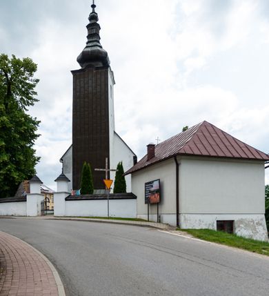 Zdjęcie nr 24: Kościół św. Piotra i św. Pawła jest usytuowany w centrum Łapsz Wyżnych, na południe od głównej drogi z Trybsza do Łapsz Niżnych. Teren przykościelny jest otoczony wysokim kamiennym i częściowo otynkowanym murem, nakrytym gontem od strony wschodniej, zachodniej i północnej oraz nakrytym blachą od strony południowej; daszki jednospadowe, nachylone na zewnątrz. W części zachodniej muru zlokalizowana jest szeroka brama, flankowana dwoma masywnymi filarami, na których ustawione są okrągłe słupy, przykryte stożkowym daszkiem gontowym i zwieńczone krzyżykami. Od wschodu analogiczne wejście z szerszym przejściem, dostępnym schodkami. Trzecie wejście na teren przykościelny prowadzi od północy przez bramę w kształcie arkady zamkniętej łukiem odcinkowym, zwieńczonej trójkątnym nadprożem, na którego szczycie ustawiony jest krzyż i wazony po bokach. Czwarte wejście zlokalizowane w zachodnio-południowym narożniku muru prowadzi przez wysokie schody z balustradą. Od zachodu w ogrodzeniu ulokowany jest budynek salki katechetycznej (dawna kostnica) wchodzącej w mur ścianą frontową. W obrębie placu przykościelnego znajdują się resztki cmentarza w postaci kamiennych i granitowych nagrobków oraz żeliwnych krzyży. 

Kościół jest orientowany, murowany, otynkowany, jednonawowy z czworoboczną wieżą w fasadzie z prezbiterium zamkniętym półkoliście. Dwuprzęsłowe prezbiterium oddziela od nawy ściana arkady tęczowej. Nawa jest szersza, trójprzęsłowa. Wnętrze artykułowane pilastrami wspierającymi sklepienie kolebkowe z lunetami na gurtach, ozdobione stiukowymi, późnobarokowymi ramami. Od południa do prezbiterium przylega zakrystia na planie prostokąta, a do nawy od północny kruchta z portalem z zaakcentowaną datą: „1760”. Na zachodniej ścianie nawy chór muzyczny wsparty jest na trzech półkolistych arkadach. 

Wnętrze oświetlają umieszczone w południowych i północnych ścianach nawy prostokątne, zamknięte półkoliście cztery okna, takie same dwa znajdują się w prezbiterium; w wieży trzy podobne okna umieszczone po jednym z każdej strony, oprócz ściany zachodniej; w apsydzie jedno małe, okrągłe okno. Do kościoła prowadzi główne wejście od strony zachodniej oraz dwa mniejsze od strony północnej przez kruchtę i od strony południowej przez zakrystię.

W zewnętrznej elewacji kościoła widoczny jest niewysoki, kamienny cokół, powyżej kościół jest otynkowany. Prezbiterium, niższe od nawy. Nawa oszkarpowana, nakryta dachem dwuspadowym z wieżą na sygnaturkę na skrzyżowaniu na wschodnim zakończeniu nawy. Do zachodniej fasady kościoła dostawiona jest wysoka założona na planie kwadratu wieża-dzwonnica. W dolnej kondygnacji na osi kościoła znajduje się prostokątne wejście do kruchty, zamknięte półkoliście. Fasada wieży w całości pokryta jest blachą, przechodzącą nad głównym wejściem do kościoła w daszek. Hełm wieży baniasty z latarnią.
