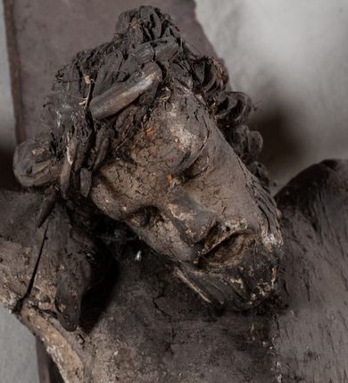 Zdjęcie nr 2: Pełnoplastyczna, ścięta w partii korpusu i bioder, polichromowana figura Chrystusa na prostym krzyżu, przybita trzema gwoździami i dodatkowym drewnianym kołkiem w partii bioder. Sylwetka zmarłego Chrystusa smukła, wychudła z wyraźnie zaznaczoną muskulaturą i układem kostnym klatki piersiowej. Ramiona uniesione wysoko tworzą łuk, nogi są lekko ugięte w kolanach, głowa opada na prawe ramię. Twarz pociągła, oczy zamknięte, nos niewielki, usta lekko otwarte. Na prawe ramię spływa pukiel długich włosów, broda krótka. Perizonium krótkie,  spięte na prawym boku.  Figura zmarłego Chrystusa pokryta polichromią imitującą naturalną karnację, widoczne są ślady męki. Perizonium ciemnobrązowe, włosy i zarost czarne.