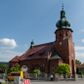 Zdjęcie nr 1: Kościół św. Jana Chrzciciela w Zembrzycach jest usytuowany na zachód od głównej drogi prowadzącej z Makowa Podhalańskiego do Wadowic i położony w centrum wsi, na placu otoczonym żeliwnym płotem na kamiennej podmurówce. Wejście na plac przykościelny prowadzi przez bramę od zachodu i wąską bramkę od północy. Kościół jest budowlą orientowaną, założoną na planie prostokąta, trójnawową, pseudohalową z prezbiterium zamkniętym trójbocznie, przy którym od północy znajduje się kaplica, a od południa piętrowa zakrystia z przedsionkiem i emporą otwartą na prezbiterium. Do nawy od strony północnej przylega wąska kruchta, nakryta dwuspadowym daszkiem. Od zachodu świątyni jest czworoboczna, masywna wieża, w górnej jednej trzeciej wysokości ośmioboczna, nakryta hełmem baniastym z latarnią. W fasadzie wysoka, półkolista wnęka z portalem i oknem termalnym. Przy wieży od północny składzik, a od południa kaplica. Ściany prezbiterium, nawy oraz elewacje aneksów w narożnikach artykułowane są szkarpami. Elewacje boczne zwieńczone ceglanym, zygzakowatym fryzem z krzyżykami. Szczyty na zakończeniach korpusu ozdobione kamiennymi szyszkami. W nawie okna trójdzielne z kamiennymi przezroczami, zamknięte łukami półkolistymi; w prezbiterium prostokątne zamknięte półkoliście. Świątynia nakryta jest dachem dwuspadowym. Na zakończeniu nawy znajduje się wieżyczka na sygnaturkę z baniastym hełmem. Wewnątrz nawy oddzielone są kolumnami z ośmiobocznymi głowicami, które wspierają sklepienia kolebkowe z lunetami. Empory i kaplice otwarte są arkadami półkolistymi. Prezbiterium podniesione jest o poziom dwóch stopni.
