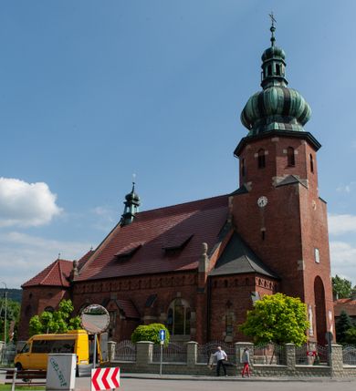 Zdjęcie nr 1: Kościół św. Jana Chrzciciela w Zembrzycach jest usytuowany na zachód od głównej drogi prowadzącej z Makowa Podhalańskiego do Wadowic i położony w centrum wsi, na placu otoczonym żeliwnym płotem na kamiennej podmurówce. Wejście na plac przykościelny prowadzi przez bramę od zachodu i wąską bramkę od północy. Kościół jest budowlą orientowaną, założoną na planie prostokąta, trójnawową, pseudohalową z prezbiterium zamkniętym trójbocznie, przy którym od północy znajduje się kaplica, a od południa piętrowa zakrystia z przedsionkiem i emporą otwartą na prezbiterium. Do nawy od strony północnej przylega wąska kruchta, nakryta dwuspadowym daszkiem. Od zachodu świątyni jest czworoboczna, masywna wieża, w górnej jednej trzeciej wysokości ośmioboczna, nakryta hełmem baniastym z latarnią. W fasadzie wysoka, półkolista wnęka z portalem i oknem termalnym. Przy wieży od północny składzik, a od południa kaplica. Ściany prezbiterium, nawy oraz elewacje aneksów w narożnikach artykułowane są szkarpami. Elewacje boczne zwieńczone ceglanym, zygzakowatym fryzem z krzyżykami. Szczyty na zakończeniach korpusu ozdobione kamiennymi szyszkami. W nawie okna trójdzielne z kamiennymi przezroczami, zamknięte łukami półkolistymi; w prezbiterium prostokątne zamknięte półkoliście. Świątynia nakryta jest dachem dwuspadowym. Na zakończeniu nawy znajduje się wieżyczka na sygnaturkę z baniastym hełmem. Wewnątrz nawy oddzielone są kolumnami z ośmiobocznymi głowicami, które wspierają sklepienia kolebkowe z lunetami. Empory i kaplice otwarte są arkadami półkolistymi. Prezbiterium podniesione jest o poziom dwóch stopni.
