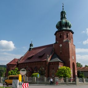 Zdjęcie nr 1: Kościół św. Jana Chrzciciela w Zembrzycach jest usytuowany na zachód od głównej drogi prowadzącej z Makowa Podhalańskiego do Wadowic i położony w centrum wsi, na placu otoczonym żeliwnym płotem na kamiennej podmurówce. Wejście na plac przykościelny prowadzi przez bramę od zachodu i wąską bramkę od północy. Kościół jest budowlą orientowaną, założoną na planie prostokąta, trójnawową, pseudohalową z prezbiterium zamkniętym trójbocznie, przy którym od północy znajduje się kaplica, a od południa piętrowa zakrystia z przedsionkiem i emporą otwartą na prezbiterium. Do nawy od strony północnej przylega wąska kruchta, nakryta dwuspadowym daszkiem. Od zachodu świątyni jest czworoboczna, masywna wieża, w górnej jednej trzeciej wysokości ośmioboczna, nakryta hełmem baniastym z latarnią. W fasadzie wysoka, półkolista wnęka z portalem i oknem termalnym. Przy wieży od północny składzik, a od południa kaplica. Ściany prezbiterium, nawy oraz elewacje aneksów w narożnikach artykułowane są szkarpami. Elewacje boczne zwieńczone ceglanym, zygzakowatym fryzem z krzyżykami. Szczyty na zakończeniach korpusu ozdobione kamiennymi szyszkami. W nawie okna trójdzielne z kamiennymi przezroczami, zamknięte łukami półkolistymi; w prezbiterium prostokątne zamknięte półkoliście. Świątynia nakryta jest dachem dwuspadowym. Na zakończeniu nawy znajduje się wieżyczka na sygnaturkę z baniastym hełmem. Wewnątrz nawy oddzielone są kolumnami z ośmiobocznymi głowicami, które wspierają sklepienia kolebkowe z lunetami. Empory i kaplice otwarte są arkadami półkolistymi. Prezbiterium podniesione jest o poziom dwóch stopni.
