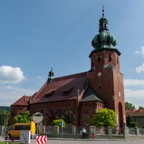 Zdjęcie nr 1: Kościół św. Jana Chrzciciela w Zembrzycach jest usytuowany na zachód od głównej drogi prowadzącej z Makowa Podhalańskiego do Wadowic i położony w centrum wsi, na placu otoczonym żeliwnym płotem na kamiennej podmurówce. Wejście na plac przykościelny prowadzi przez bramę od zachodu i wąską bramkę od północy. Kościół jest budowlą orientowaną, założoną na planie prostokąta, trójnawową, pseudohalową z prezbiterium zamkniętym trójbocznie, przy którym od północy znajduje się kaplica, a od południa piętrowa zakrystia z przedsionkiem i emporą otwartą na prezbiterium. Do nawy od strony północnej przylega wąska kruchta, nakryta dwuspadowym daszkiem. Od zachodu świątyni jest czworoboczna, masywna wieża, w górnej jednej trzeciej wysokości ośmioboczna, nakryta hełmem baniastym z latarnią. W fasadzie wysoka, półkolista wnęka z portalem i oknem termalnym. Przy wieży od północny składzik, a od południa kaplica. Ściany prezbiterium, nawy oraz elewacje aneksów w narożnikach artykułowane są szkarpami. Elewacje boczne zwieńczone ceglanym, zygzakowatym fryzem z krzyżykami. Szczyty na zakończeniach korpusu ozdobione kamiennymi szyszkami. W nawie okna trójdzielne z kamiennymi przezroczami, zamknięte łukami półkolistymi; w prezbiterium prostokątne zamknięte półkoliście. Świątynia nakryta jest dachem dwuspadowym. Na zakończeniu nawy znajduje się wieżyczka na sygnaturkę z baniastym hełmem. Wewnątrz nawy oddzielone są kolumnami z ośmiobocznymi głowicami, które wspierają sklepienia kolebkowe z lunetami. Empory i kaplice otwarte są arkadami półkolistymi. Prezbiterium podniesione jest o poziom dwóch stopni.
