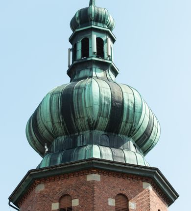 Zdjęcie nr 15: Kościół św. Jana Chrzciciela w Zembrzycach jest usytuowany na zachód od głównej drogi prowadzącej z Makowa Podhalańskiego do Wadowic i położony w centrum wsi, na placu otoczonym żeliwnym płotem na kamiennej podmurówce. Wejście na plac przykościelny prowadzi przez bramę od zachodu i wąską bramkę od północy. Kościół jest budowlą orientowaną, założoną na planie prostokąta, trójnawową, pseudohalową z prezbiterium zamkniętym trójbocznie, przy którym od północy znajduje się kaplica, a od południa piętrowa zakrystia z przedsionkiem i emporą otwartą na prezbiterium. Do nawy od strony północnej przylega wąska kruchta, nakryta dwuspadowym daszkiem. Od zachodu świątyni jest czworoboczna, masywna wieża, w górnej jednej trzeciej wysokości ośmioboczna, nakryta hełmem baniastym z latarnią. W fasadzie wysoka, półkolista wnęka z portalem i oknem termalnym. Przy wieży od północny składzik, a od południa kaplica. Ściany prezbiterium, nawy oraz elewacje aneksów w narożnikach artykułowane są szkarpami. Elewacje boczne zwieńczone ceglanym, zygzakowatym fryzem z krzyżykami. Szczyty na zakończeniach korpusu ozdobione kamiennymi szyszkami. W nawie okna trójdzielne z kamiennymi przezroczami, zamknięte łukami półkolistymi; w prezbiterium prostokątne zamknięte półkoliście. Świątynia nakryta jest dachem dwuspadowym. Na zakończeniu nawy znajduje się wieżyczka na sygnaturkę z baniastym hełmem. Wewnątrz nawy oddzielone są kolumnami z ośmiobocznymi głowicami, które wspierają sklepienia kolebkowe z lunetami. Empory i kaplice otwarte są arkadami półkolistymi. Prezbiterium podniesione jest o poziom dwóch stopni.
