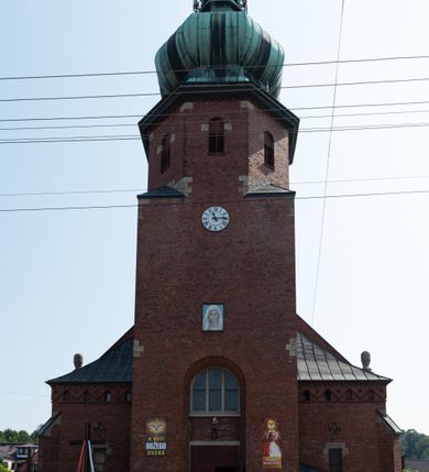 Zdjęcie nr 12: Kościół św. Jana Chrzciciela w Zembrzycach jest usytuowany na zachód od głównej drogi prowadzącej z Makowa Podhalańskiego do Wadowic i położony w centrum wsi, na placu otoczonym żeliwnym płotem na kamiennej podmurówce. Wejście na plac przykościelny prowadzi przez bramę od zachodu i wąską bramkę od północy. Kościół jest budowlą orientowaną, założoną na planie prostokąta, trójnawową, pseudohalową z prezbiterium zamkniętym trójbocznie, przy którym od północy znajduje się kaplica, a od południa piętrowa zakrystia z przedsionkiem i emporą otwartą na prezbiterium. Do nawy od strony północnej przylega wąska kruchta, nakryta dwuspadowym daszkiem. Od zachodu świątyni jest czworoboczna, masywna wieża, w górnej jednej trzeciej wysokości ośmioboczna, nakryta hełmem baniastym z latarnią. W fasadzie wysoka, półkolista wnęka z portalem i oknem termalnym. Przy wieży od północny składzik, a od południa kaplica. Ściany prezbiterium, nawy oraz elewacje aneksów w narożnikach artykułowane są szkarpami. Elewacje boczne zwieńczone ceglanym, zygzakowatym fryzem z krzyżykami. Szczyty na zakończeniach korpusu ozdobione kamiennymi szyszkami. W nawie okna trójdzielne z kamiennymi przezroczami, zamknięte łukami półkolistymi; w prezbiterium prostokątne zamknięte półkoliście. Świątynia nakryta jest dachem dwuspadowym. Na zakończeniu nawy znajduje się wieżyczka na sygnaturkę z baniastym hełmem. Wewnątrz nawy oddzielone są kolumnami z ośmiobocznymi głowicami, które wspierają sklepienia kolebkowe z lunetami. Empory i kaplice otwarte są arkadami półkolistymi. Prezbiterium podniesione jest o poziom dwóch stopni.
