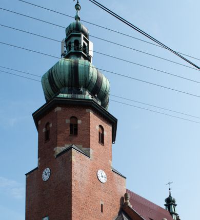 Zdjęcie nr 16: Kościół św. Jana Chrzciciela w Zembrzycach jest usytuowany na zachód od głównej drogi prowadzącej z Makowa Podhalańskiego do Wadowic i położony w centrum wsi, na placu otoczonym żeliwnym płotem na kamiennej podmurówce. Wejście na plac przykościelny prowadzi przez bramę od zachodu i wąską bramkę od północy. Kościół jest budowlą orientowaną, założoną na planie prostokąta, trójnawową, pseudohalową z prezbiterium zamkniętym trójbocznie, przy którym od północy znajduje się kaplica, a od południa piętrowa zakrystia z przedsionkiem i emporą otwartą na prezbiterium. Do nawy od strony północnej przylega wąska kruchta, nakryta dwuspadowym daszkiem. Od zachodu świątyni jest czworoboczna, masywna wieża, w górnej jednej trzeciej wysokości ośmioboczna, nakryta hełmem baniastym z latarnią. W fasadzie wysoka, półkolista wnęka z portalem i oknem termalnym. Przy wieży od północny składzik, a od południa kaplica. Ściany prezbiterium, nawy oraz elewacje aneksów w narożnikach artykułowane są szkarpami. Elewacje boczne zwieńczone ceglanym, zygzakowatym fryzem z krzyżykami. Szczyty na zakończeniach korpusu ozdobione kamiennymi szyszkami. W nawie okna trójdzielne z kamiennymi przezroczami, zamknięte łukami półkolistymi; w prezbiterium prostokątne zamknięte półkoliście. Świątynia nakryta jest dachem dwuspadowym. Na zakończeniu nawy znajduje się wieżyczka na sygnaturkę z baniastym hełmem. Wewnątrz nawy oddzielone są kolumnami z ośmiobocznymi głowicami, które wspierają sklepienia kolebkowe z lunetami. Empory i kaplice otwarte są arkadami półkolistymi. Prezbiterium podniesione jest o poziom dwóch stopni.
