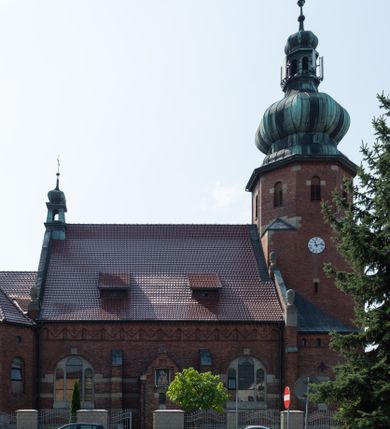 Zdjęcie nr 3: Kościół św. Jana Chrzciciela w Zembrzycach jest usytuowany na zachód od głównej drogi prowadzącej z Makowa Podhalańskiego do Wadowic i położony w centrum wsi, na placu otoczonym żeliwnym płotem na kamiennej podmurówce. Wejście na plac przykościelny prowadzi przez bramę od zachodu i wąską bramkę od północy. Kościół jest budowlą orientowaną, założoną na planie prostokąta, trójnawową, pseudohalową z prezbiterium zamkniętym trójbocznie, przy którym od północy znajduje się kaplica, a od południa piętrowa zakrystia z przedsionkiem i emporą otwartą na prezbiterium. Do nawy od strony północnej przylega wąska kruchta, nakryta dwuspadowym daszkiem. Od zachodu świątyni jest czworoboczna, masywna wieża, w górnej jednej trzeciej wysokości ośmioboczna, nakryta hełmem baniastym z latarnią. W fasadzie wysoka, półkolista wnęka z portalem i oknem termalnym. Przy wieży od północny składzik, a od południa kaplica. Ściany prezbiterium, nawy oraz elewacje aneksów w narożnikach artykułowane są szkarpami. Elewacje boczne zwieńczone ceglanym, zygzakowatym fryzem z krzyżykami. Szczyty na zakończeniach korpusu ozdobione kamiennymi szyszkami. W nawie okna trójdzielne z kamiennymi przezroczami, zamknięte łukami półkolistymi; w prezbiterium prostokątne zamknięte półkoliście. Świątynia nakryta jest dachem dwuspadowym. Na zakończeniu nawy znajduje się wieżyczka na sygnaturkę z baniastym hełmem. Wewnątrz nawy oddzielone są kolumnami z ośmiobocznymi głowicami, które wspierają sklepienia kolebkowe z lunetami. Empory i kaplice otwarte są arkadami półkolistymi. Prezbiterium podniesione jest o poziom dwóch stopni.
