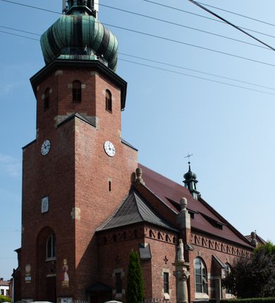 Zdjęcie nr 9: Kościół św. Jana Chrzciciela w Zembrzycach jest usytuowany na zachód od głównej drogi prowadzącej z Makowa Podhalańskiego do Wadowic i położony w centrum wsi, na placu otoczonym żeliwnym płotem na kamiennej podmurówce. Wejście na plac przykościelny prowadzi przez bramę od zachodu i wąską bramkę od północy. Kościół jest budowlą orientowaną, założoną na planie prostokąta, trójnawową, pseudohalową z prezbiterium zamkniętym trójbocznie, przy którym od północy znajduje się kaplica, a od południa piętrowa zakrystia z przedsionkiem i emporą otwartą na prezbiterium. Do nawy od strony północnej przylega wąska kruchta, nakryta dwuspadowym daszkiem. Od zachodu świątyni jest czworoboczna, masywna wieża, w górnej jednej trzeciej wysokości ośmioboczna, nakryta hełmem baniastym z latarnią. W fasadzie wysoka, półkolista wnęka z portalem i oknem termalnym. Przy wieży od północny składzik, a od południa kaplica. Ściany prezbiterium, nawy oraz elewacje aneksów w narożnikach artykułowane są szkarpami. Elewacje boczne zwieńczone ceglanym, zygzakowatym fryzem z krzyżykami. Szczyty na zakończeniach korpusu ozdobione kamiennymi szyszkami. W nawie okna trójdzielne z kamiennymi przezroczami, zamknięte łukami półkolistymi; w prezbiterium prostokątne zamknięte półkoliście. Świątynia nakryta jest dachem dwuspadowym. Na zakończeniu nawy znajduje się wieżyczka na sygnaturkę z baniastym hełmem. Wewnątrz nawy oddzielone są kolumnami z ośmiobocznymi głowicami, które wspierają sklepienia kolebkowe z lunetami. Empory i kaplice otwarte są arkadami półkolistymi. Prezbiterium podniesione jest o poziom dwóch stopni.
