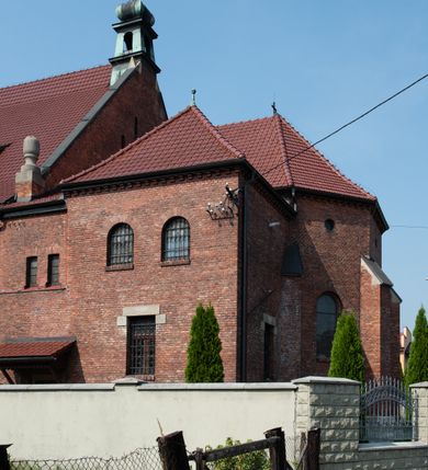 Zdjęcie nr 31: Kościół św. Jana Chrzciciela w Zembrzycach jest usytuowany na zachód od głównej drogi prowadzącej z Makowa Podhalańskiego do Wadowic i położony w centrum wsi, na placu otoczonym żeliwnym płotem na kamiennej podmurówce. Wejście na plac przykościelny prowadzi przez bramę od zachodu i wąską bramkę od północy. Kościół jest budowlą orientowaną, założoną na planie prostokąta, trójnawową, pseudohalową z prezbiterium zamkniętym trójbocznie, przy którym od północy znajduje się kaplica, a od południa piętrowa zakrystia z przedsionkiem i emporą otwartą na prezbiterium. Do nawy od strony północnej przylega wąska kruchta, nakryta dwuspadowym daszkiem. Od zachodu świątyni jest czworoboczna, masywna wieża, w górnej jednej trzeciej wysokości ośmioboczna, nakryta hełmem baniastym z latarnią. W fasadzie wysoka, półkolista wnęka z portalem i oknem termalnym. Przy wieży od północny składzik, a od południa kaplica. Ściany prezbiterium, nawy oraz elewacje aneksów w narożnikach artykułowane są szkarpami. Elewacje boczne zwieńczone ceglanym, zygzakowatym fryzem z krzyżykami. Szczyty na zakończeniach korpusu ozdobione kamiennymi szyszkami. W nawie okna trójdzielne z kamiennymi przezroczami, zamknięte łukami półkolistymi; w prezbiterium prostokątne zamknięte półkoliście. Świątynia nakryta jest dachem dwuspadowym. Na zakończeniu nawy znajduje się wieżyczka na sygnaturkę z baniastym hełmem. Wewnątrz nawy oddzielone są kolumnami z ośmiobocznymi głowicami, które wspierają sklepienia kolebkowe z lunetami. Empory i kaplice otwarte są arkadami półkolistymi. Prezbiterium podniesione jest o poziom dwóch stopni.
