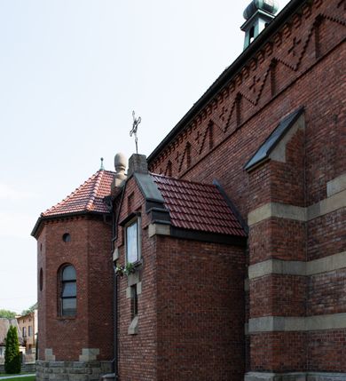 Zdjęcie nr 33: Kościół św. Jana Chrzciciela w Zembrzycach jest usytuowany na zachód od głównej drogi prowadzącej z Makowa Podhalańskiego do Wadowic i położony w centrum wsi, na placu otoczonym żeliwnym płotem na kamiennej podmurówce. Wejście na plac przykościelny prowadzi przez bramę od zachodu i wąską bramkę od północy. Kościół jest budowlą orientowaną, założoną na planie prostokąta, trójnawową, pseudohalową z prezbiterium zamkniętym trójbocznie, przy którym od północy znajduje się kaplica, a od południa piętrowa zakrystia z przedsionkiem i emporą otwartą na prezbiterium. Do nawy od strony północnej przylega wąska kruchta, nakryta dwuspadowym daszkiem. Od zachodu świątyni jest czworoboczna, masywna wieża, w górnej jednej trzeciej wysokości ośmioboczna, nakryta hełmem baniastym z latarnią. W fasadzie wysoka, półkolista wnęka z portalem i oknem termalnym. Przy wieży od północny składzik, a od południa kaplica. Ściany prezbiterium, nawy oraz elewacje aneksów w narożnikach artykułowane są szkarpami. Elewacje boczne zwieńczone ceglanym, zygzakowatym fryzem z krzyżykami. Szczyty na zakończeniach korpusu ozdobione kamiennymi szyszkami. W nawie okna trójdzielne z kamiennymi przezroczami, zamknięte łukami półkolistymi; w prezbiterium prostokątne zamknięte półkoliście. Świątynia nakryta jest dachem dwuspadowym. Na zakończeniu nawy znajduje się wieżyczka na sygnaturkę z baniastym hełmem. Wewnątrz nawy oddzielone są kolumnami z ośmiobocznymi głowicami, które wspierają sklepienia kolebkowe z lunetami. Empory i kaplice otwarte są arkadami półkolistymi. Prezbiterium podniesione jest o poziom dwóch stopni.
