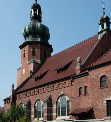 Zdjęcie nr 32: Kościół św. Jana Chrzciciela w Zembrzycach jest usytuowany na zachód od głównej drogi prowadzącej z Makowa Podhalańskiego do Wadowic i położony w centrum wsi, na placu otoczonym żeliwnym płotem na kamiennej podmurówce. Wejście na plac przykościelny prowadzi przez bramę od zachodu i wąską bramkę od północy. Kościół jest budowlą orientowaną, założoną na planie prostokąta, trójnawową, pseudohalową z prezbiterium zamkniętym trójbocznie, przy którym od północy znajduje się kaplica, a od południa piętrowa zakrystia z przedsionkiem i emporą otwartą na prezbiterium. Do nawy od strony północnej przylega wąska kruchta, nakryta dwuspadowym daszkiem. Od zachodu świątyni jest czworoboczna, masywna wieża, w górnej jednej trzeciej wysokości ośmioboczna, nakryta hełmem baniastym z latarnią. W fasadzie wysoka, półkolista wnęka z portalem i oknem termalnym. Przy wieży od północny składzik, a od południa kaplica. Ściany prezbiterium, nawy oraz elewacje aneksów w narożnikach artykułowane są szkarpami. Elewacje boczne zwieńczone ceglanym, zygzakowatym fryzem z krzyżykami. Szczyty na zakończeniach korpusu ozdobione kamiennymi szyszkami. W nawie okna trójdzielne z kamiennymi przezroczami, zamknięte łukami półkolistymi; w prezbiterium prostokątne zamknięte półkoliście. Świątynia nakryta jest dachem dwuspadowym. Na zakończeniu nawy znajduje się wieżyczka na sygnaturkę z baniastym hełmem. Wewnątrz nawy oddzielone są kolumnami z ośmiobocznymi głowicami, które wspierają sklepienia kolebkowe z lunetami. Empory i kaplice otwarte są arkadami półkolistymi. Prezbiterium podniesione jest o poziom dwóch stopni.
