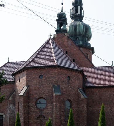 Zdjęcie nr 35: Kościół św. Jana Chrzciciela w Zembrzycach jest usytuowany na zachód od głównej drogi prowadzącej z Makowa Podhalańskiego do Wadowic i położony w centrum wsi, na placu otoczonym żeliwnym płotem na kamiennej podmurówce. Wejście na plac przykościelny prowadzi przez bramę od zachodu i wąską bramkę od północy. Kościół jest budowlą orientowaną, założoną na planie prostokąta, trójnawową, pseudohalową z prezbiterium zamkniętym trójbocznie, przy którym od północy znajduje się kaplica, a od południa piętrowa zakrystia z przedsionkiem i emporą otwartą na prezbiterium. Do nawy od strony północnej przylega wąska kruchta, nakryta dwuspadowym daszkiem. Od zachodu świątyni jest czworoboczna, masywna wieża, w górnej jednej trzeciej wysokości ośmioboczna, nakryta hełmem baniastym z latarnią. W fasadzie wysoka, półkolista wnęka z portalem i oknem termalnym. Przy wieży od północny składzik, a od południa kaplica. Ściany prezbiterium, nawy oraz elewacje aneksów w narożnikach artykułowane są szkarpami. Elewacje boczne zwieńczone ceglanym, zygzakowatym fryzem z krzyżykami. Szczyty na zakończeniach korpusu ozdobione kamiennymi szyszkami. W nawie okna trójdzielne z kamiennymi przezroczami, zamknięte łukami półkolistymi; w prezbiterium prostokątne zamknięte półkoliście. Świątynia nakryta jest dachem dwuspadowym. Na zakończeniu nawy znajduje się wieżyczka na sygnaturkę z baniastym hełmem. Wewnątrz nawy oddzielone są kolumnami z ośmiobocznymi głowicami, które wspierają sklepienia kolebkowe z lunetami. Empory i kaplice otwarte są arkadami półkolistymi. Prezbiterium podniesione jest o poziom dwóch stopni.
