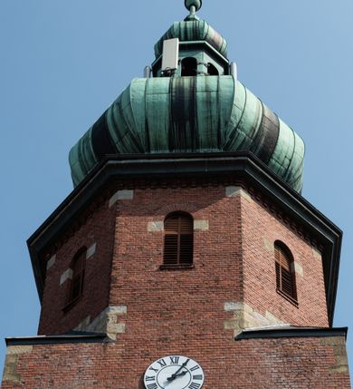 Zdjęcie nr 18: Kościół św. Jana Chrzciciela w Zembrzycach jest usytuowany na zachód od głównej drogi prowadzącej z Makowa Podhalańskiego do Wadowic i położony w centrum wsi, na placu otoczonym żeliwnym płotem na kamiennej podmurówce. Wejście na plac przykościelny prowadzi przez bramę od zachodu i wąską bramkę od północy. Kościół jest budowlą orientowaną, założoną na planie prostokąta, trójnawową, pseudohalową z prezbiterium zamkniętym trójbocznie, przy którym od północy znajduje się kaplica, a od południa piętrowa zakrystia z przedsionkiem i emporą otwartą na prezbiterium. Do nawy od strony północnej przylega wąska kruchta, nakryta dwuspadowym daszkiem. Od zachodu świątyni jest czworoboczna, masywna wieża, w górnej jednej trzeciej wysokości ośmioboczna, nakryta hełmem baniastym z latarnią. W fasadzie wysoka, półkolista wnęka z portalem i oknem termalnym. Przy wieży od północny składzik, a od południa kaplica. Ściany prezbiterium, nawy oraz elewacje aneksów w narożnikach artykułowane są szkarpami. Elewacje boczne zwieńczone ceglanym, zygzakowatym fryzem z krzyżykami. Szczyty na zakończeniach korpusu ozdobione kamiennymi szyszkami. W nawie okna trójdzielne z kamiennymi przezroczami, zamknięte łukami półkolistymi; w prezbiterium prostokątne zamknięte półkoliście. Świątynia nakryta jest dachem dwuspadowym. Na zakończeniu nawy znajduje się wieżyczka na sygnaturkę z baniastym hełmem. Wewnątrz nawy oddzielone są kolumnami z ośmiobocznymi głowicami, które wspierają sklepienia kolebkowe z lunetami. Empory i kaplice otwarte są arkadami półkolistymi. Prezbiterium podniesione jest o poziom dwóch stopni.
