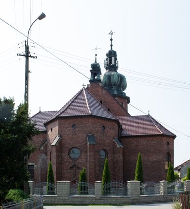 Zdjęcie nr 37: Kościół św. Jana Chrzciciela w Zembrzycach jest usytuowany na zachód od głównej drogi prowadzącej z Makowa Podhalańskiego do Wadowic i położony w centrum wsi, na placu otoczonym żeliwnym płotem na kamiennej podmurówce. Wejście na plac przykościelny prowadzi przez bramę od zachodu i wąską bramkę od północy. Kościół jest budowlą orientowaną, założoną na planie prostokąta, trójnawową, pseudohalową z prezbiterium zamkniętym trójbocznie, przy którym od północy znajduje się kaplica, a od południa piętrowa zakrystia z przedsionkiem i emporą otwartą na prezbiterium. Do nawy od strony północnej przylega wąska kruchta, nakryta dwuspadowym daszkiem. Od zachodu świątyni jest czworoboczna, masywna wieża, w górnej jednej trzeciej wysokości ośmioboczna, nakryta hełmem baniastym z latarnią. W fasadzie wysoka, półkolista wnęka z portalem i oknem termalnym. Przy wieży od północny składzik, a od południa kaplica. Ściany prezbiterium, nawy oraz elewacje aneksów w narożnikach artykułowane są szkarpami. Elewacje boczne zwieńczone ceglanym, zygzakowatym fryzem z krzyżykami. Szczyty na zakończeniach korpusu ozdobione kamiennymi szyszkami. W nawie okna trójdzielne z kamiennymi przezroczami, zamknięte łukami półkolistymi; w prezbiterium prostokątne zamknięte półkoliście. Świątynia nakryta jest dachem dwuspadowym. Na zakończeniu nawy znajduje się wieżyczka na sygnaturkę z baniastym hełmem. Wewnątrz nawy oddzielone są kolumnami z ośmiobocznymi głowicami, które wspierają sklepienia kolebkowe z lunetami. Empory i kaplice otwarte są arkadami półkolistymi. Prezbiterium podniesione jest o poziom dwóch stopni.
