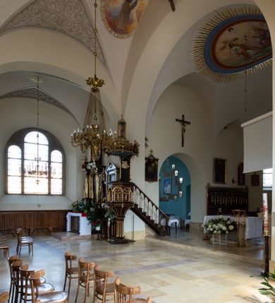 Zdjęcie nr 56: Kościół św. Jana Chrzciciela w Zembrzycach jest usytuowany na zachód od głównej drogi prowadzącej z Makowa Podhalańskiego do Wadowic i położony w centrum wsi, na placu otoczonym żeliwnym płotem na kamiennej podmurówce. Wejście na plac przykościelny prowadzi przez bramę od zachodu i wąską bramkę od północy. Kościół jest budowlą orientowaną, założoną na planie prostokąta, trójnawową, pseudohalową z prezbiterium zamkniętym trójbocznie, przy którym od północy znajduje się kaplica, a od południa piętrowa zakrystia z przedsionkiem i emporą otwartą na prezbiterium. Do nawy od strony północnej przylega wąska kruchta, nakryta dwuspadowym daszkiem. Od zachodu świątyni jest czworoboczna, masywna wieża, w górnej jednej trzeciej wysokości ośmioboczna, nakryta hełmem baniastym z latarnią. W fasadzie wysoka, półkolista wnęka z portalem i oknem termalnym. Przy wieży od północny składzik, a od południa kaplica. Ściany prezbiterium, nawy oraz elewacje aneksów w narożnikach artykułowane są szkarpami. Elewacje boczne zwieńczone ceglanym, zygzakowatym fryzem z krzyżykami. Szczyty na zakończeniach korpusu ozdobione kamiennymi szyszkami. W nawie okna trójdzielne z kamiennymi przezroczami, zamknięte łukami półkolistymi; w prezbiterium prostokątne zamknięte półkoliście. Świątynia nakryta jest dachem dwuspadowym. Na zakończeniu nawy znajduje się wieżyczka na sygnaturkę z baniastym hełmem. Wewnątrz nawy oddzielone są kolumnami z ośmiobocznymi głowicami, które wspierają sklepienia kolebkowe z lunetami. Empory i kaplice otwarte są arkadami półkolistymi. Prezbiterium podniesione jest o poziom dwóch stopni.
