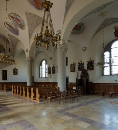 Zdjęcie nr 60: Kościół św. Jana Chrzciciela w Zembrzycach jest usytuowany na zachód od głównej drogi prowadzącej z Makowa Podhalańskiego do Wadowic i położony w centrum wsi, na placu otoczonym żeliwnym płotem na kamiennej podmurówce. Wejście na plac przykościelny prowadzi przez bramę od zachodu i wąską bramkę od północy. Kościół jest budowlą orientowaną, założoną na planie prostokąta, trójnawową, pseudohalową z prezbiterium zamkniętym trójbocznie, przy którym od północy znajduje się kaplica, a od południa piętrowa zakrystia z przedsionkiem i emporą otwartą na prezbiterium. Do nawy od strony północnej przylega wąska kruchta, nakryta dwuspadowym daszkiem. Od zachodu świątyni jest czworoboczna, masywna wieża, w górnej jednej trzeciej wysokości ośmioboczna, nakryta hełmem baniastym z latarnią. W fasadzie wysoka, półkolista wnęka z portalem i oknem termalnym. Przy wieży od północny składzik, a od południa kaplica. Ściany prezbiterium, nawy oraz elewacje aneksów w narożnikach artykułowane są szkarpami. Elewacje boczne zwieńczone ceglanym, zygzakowatym fryzem z krzyżykami. Szczyty na zakończeniach korpusu ozdobione kamiennymi szyszkami. W nawie okna trójdzielne z kamiennymi przezroczami, zamknięte łukami półkolistymi; w prezbiterium prostokątne zamknięte półkoliście. Świątynia nakryta jest dachem dwuspadowym. Na zakończeniu nawy znajduje się wieżyczka na sygnaturkę z baniastym hełmem. Wewnątrz nawy oddzielone są kolumnami z ośmiobocznymi głowicami, które wspierają sklepienia kolebkowe z lunetami. Empory i kaplice otwarte są arkadami półkolistymi. Prezbiterium podniesione jest o poziom dwóch stopni.
