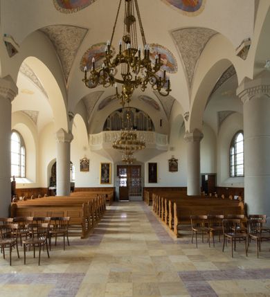 Zdjęcie nr 65: Kościół św. Jana Chrzciciela w Zembrzycach jest usytuowany na zachód od głównej drogi prowadzącej z Makowa Podhalańskiego do Wadowic i położony w centrum wsi, na placu otoczonym żeliwnym płotem na kamiennej podmurówce. Wejście na plac przykościelny prowadzi przez bramę od zachodu i wąską bramkę od północy. Kościół jest budowlą orientowaną, założoną na planie prostokąta, trójnawową, pseudohalową z prezbiterium zamkniętym trójbocznie, przy którym od północy znajduje się kaplica, a od południa piętrowa zakrystia z przedsionkiem i emporą otwartą na prezbiterium. Do nawy od strony północnej przylega wąska kruchta, nakryta dwuspadowym daszkiem. Od zachodu świątyni jest czworoboczna, masywna wieża, w górnej jednej trzeciej wysokości ośmioboczna, nakryta hełmem baniastym z latarnią. W fasadzie wysoka, półkolista wnęka z portalem i oknem termalnym. Przy wieży od północny składzik, a od południa kaplica. Ściany prezbiterium, nawy oraz elewacje aneksów w narożnikach artykułowane są szkarpami. Elewacje boczne zwieńczone ceglanym, zygzakowatym fryzem z krzyżykami. Szczyty na zakończeniach korpusu ozdobione kamiennymi szyszkami. W nawie okna trójdzielne z kamiennymi przezroczami, zamknięte łukami półkolistymi; w prezbiterium prostokątne zamknięte półkoliście. Świątynia nakryta jest dachem dwuspadowym. Na zakończeniu nawy znajduje się wieżyczka na sygnaturkę z baniastym hełmem. Wewnątrz nawy oddzielone są kolumnami z ośmiobocznymi głowicami, które wspierają sklepienia kolebkowe z lunetami. Empory i kaplice otwarte są arkadami półkolistymi. Prezbiterium podniesione jest o poziom dwóch stopni.
