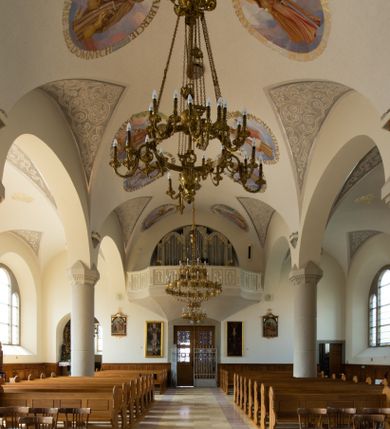 Zdjęcie nr 63: Kościół św. Jana Chrzciciela w Zembrzycach jest usytuowany na zachód od głównej drogi prowadzącej z Makowa Podhalańskiego do Wadowic i położony w centrum wsi, na placu otoczonym żeliwnym płotem na kamiennej podmurówce. Wejście na plac przykościelny prowadzi przez bramę od zachodu i wąską bramkę od północy. Kościół jest budowlą orientowaną, założoną na planie prostokąta, trójnawową, pseudohalową z prezbiterium zamkniętym trójbocznie, przy którym od północy znajduje się kaplica, a od południa piętrowa zakrystia z przedsionkiem i emporą otwartą na prezbiterium. Do nawy od strony północnej przylega wąska kruchta, nakryta dwuspadowym daszkiem. Od zachodu świątyni jest czworoboczna, masywna wieża, w górnej jednej trzeciej wysokości ośmioboczna, nakryta hełmem baniastym z latarnią. W fasadzie wysoka, półkolista wnęka z portalem i oknem termalnym. Przy wieży od północny składzik, a od południa kaplica. Ściany prezbiterium, nawy oraz elewacje aneksów w narożnikach artykułowane są szkarpami. Elewacje boczne zwieńczone ceglanym, zygzakowatym fryzem z krzyżykami. Szczyty na zakończeniach korpusu ozdobione kamiennymi szyszkami. W nawie okna trójdzielne z kamiennymi przezroczami, zamknięte łukami półkolistymi; w prezbiterium prostokątne zamknięte półkoliście. Świątynia nakryta jest dachem dwuspadowym. Na zakończeniu nawy znajduje się wieżyczka na sygnaturkę z baniastym hełmem. Wewnątrz nawy oddzielone są kolumnami z ośmiobocznymi głowicami, które wspierają sklepienia kolebkowe z lunetami. Empory i kaplice otwarte są arkadami półkolistymi. Prezbiterium podniesione jest o poziom dwóch stopni.
