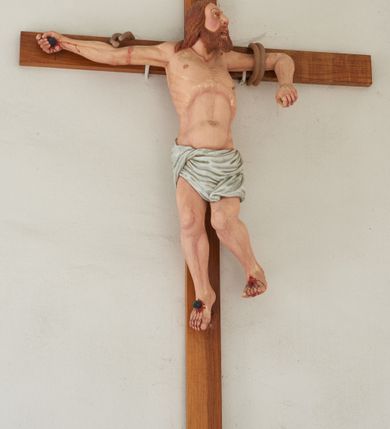 Zdjęcie nr 2: Rzeźba Złego Łotra na krzyżu ukazana w ekspresyjnej pozie o esowato wygiętej sylwetce z głową zwróconą w lewo. Ramiona ułożone wzdłuż patibulum, przywiązane do niego podwójnym sznurem (na prawej ręce urwanym). Prawa ręka wyprostowana i przybita gwoździem do krzyża, a lewa zgięta w łokciu z przedramieniem zwróconym w dół; dłonie zaciśnięte. Klatka piersiowa szeroka o wyraźnie podkreślonej linii żeber i mostka z głęboko zaznaczonym wcięciem w talii. Prawa noga przybita do krzyża jednym gwoździem, lewa ugięta w kolanie i uniesiona bok z raną po gwoździu w stopie. Twarz podłużna, okolona brodą; usta otwarte i ukazujące rzędy białych zębów; duże, szeroko otwarte oczy; szeroki nos; długie i jasnobrązowe włosy. Łotr przewiązany jest w biodrach białą, drapowaną, ciasno opinającą biodra przepaską. Na stopach i prawej dłoni widoczne są ślady krwi. Polichromia rzeźby jest naturalistyczna; krzyż drewniany, gładki.