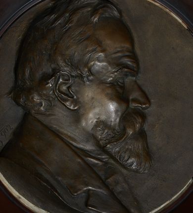 Zdjęcie nr 3: Epitafium w kształcie stojącego prostokąta, dwustopniowe, oddzielone wąskim gzymsem, zamknięte łukiem półkolistym, na którego zakończeniach dwie puste tarcze herbowe. W dolnej części epitafium płycina w kształcie leżącego prostokąta o fantazyjnym wykroju, w narożach ujęta dwiema czołgankami, z inskrypcją w polu: „LUDWIK BEŁTOWSKI / UR[ODZONY] 1819 WE LWOWIE ZASŁ[UŻONY] OBYW[ATEL] DŁUG[O]L[ETNI] RADNY MIASTA / NOWEGO TARGU MISTRZ ART[YSTA] BUD[OWLI] MECH[ANICZNYCH] PRZEM[YSŁOWYCH] PRZEWODN[ICZĄCY] / POW[IATOWEGO] STOW[ARZYSZENIA] RĘKODZ[IĘLNIKÓW] PRZEM[YSŁOWYCH] SĄDU POLUB[OWNEGO] INICIAT[OR] CZYNN[Y] ORĘD[OWNIK] / POWIĘKSZ[ANIA] MAJ[ĄTKU] DOBROBYTU GMINY UPIĘKSZ[ANIA] MIASTA OFIARN[Y] / PATRIOT[A] MĄŻ RZADK[ICH] CNÓT SERC[A] WIELK[IEGO] CHAR[AKTERU] ZM[ARŁ] 13. STYCZ[NIA] 1902 / PROSI O WESTCHNIENIE DO BOGA AMEN”. W prawym dolnym rogu epitafium sygnatura „Juliusz B[ełtowski] 1904.” Powyżej kwadratowy odlew z przedstawieniem Miłosiernego Samarytanina, flankowany dwiema popiersiami: rzeźbą Matki Boskiej z Dzieciątkiem po prawej i św. Józefa Robotnika po lewej. W dolnej części odlewu litery „D[EO] O[PTIMO] M[AXIMO]”. Na odlewie ukazany leżący na ziemi mężczyzna o wychudzonej posturze, któremu Samarytanin podaje kubek z wodą do picia. Po lewej stronie obrazu głowa wielbłąda. Matka Boska zwrócona trzy czwarte w lewo, z głową pochyloną w dół, przytulająca do piersi śpiące Dzieciątko. W dłoniach trzyma księgę. Twarz o wyraźnych rysach z długim nosem i zaciśniętymi ustami. Ubrana jest w suknię z długimi rękawami i płaszcz założony na głowę. Święty Józef zwrócony jest delikatnie w prawo z głową skierowaną w lewo. Ma krótkie i bujne włosy, wzrok skierowany w prawo oraz zaciśnięte usta. Ubrany jest w strój robotnika – koszulę z podwiniętymi do łokci rękawami. W dłoniach trzyma strug i piłę do drewna. W górnej części epitafium znajduje się okrągłe popiersie Ludwika Bełtowskiego w szerokiej okrągłej ramie. Zmarły ukazany z prawego profilu o podłużnej twarzy ze spiczastą brodą i wąsami, długim nosem i zmarszczonym czołem. Włosy krótkie. Ubrany jest w koszulę i marynarkę. Po lewej stronie popiersia sygnatura „B[ełtowski] [1]902”.


