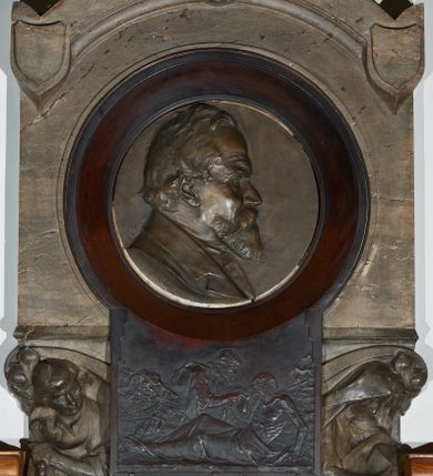 Zdjęcie nr 1: Epitafium w kształcie stojącego prostokąta, dwustopniowe, oddzielone wąskim gzymsem, zamknięte łukiem półkolistym, na którego zakończeniach dwie puste tarcze herbowe. W dolnej części epitafium płycina w kształcie leżącego prostokąta o fantazyjnym wykroju, w narożach ujęta dwiema czołgankami, z inskrypcją w polu: „LUDWIK BEŁTOWSKI / UR[ODZONY] 1819 WE LWOWIE ZASŁ[UŻONY] OBYW[ATEL] DŁUG[O]L[ETNI] RADNY MIASTA / NOWEGO TARGU MISTRZ ART[YSTA] BUD[OWLI] MECH[ANICZNYCH] PRZEM[YSŁOWYCH] PRZEWODN[ICZĄCY] / POW[IATOWEGO] STOW[ARZYSZENIA] RĘKODZ[IĘLNIKÓW] PRZEM[YSŁOWYCH] SĄDU POLUB[OWNEGO] INICIAT[OR] CZYNN[Y] ORĘD[OWNIK] / POWIĘKSZ[ANIA] MAJ[ĄTKU] DOBROBYTU GMINY UPIĘKSZ[ANIA] MIASTA OFIARN[Y] / PATRIOT[A] MĄŻ RZADK[ICH] CNÓT SERC[A] WIELK[IEGO] CHAR[AKTERU] ZM[ARŁ] 13. STYCZ[NIA] 1902 / PROSI O WESTCHNIENIE DO BOGA AMEN”. W prawym dolnym rogu epitafium sygnatura „Juliusz B[ełtowski] 1904.” Powyżej kwadratowy odlew z przedstawieniem Miłosiernego Samarytanina, flankowany dwiema popiersiami: rzeźbą Matki Boskiej z Dzieciątkiem po prawej i św. Józefa Robotnika po lewej. W dolnej części odlewu litery „D[EO] O[PTIMO] M[AXIMO]”. Na odlewie ukazany leżący na ziemi mężczyzna o wychudzonej posturze, któremu Samarytanin podaje kubek z wodą do picia. Po lewej stronie obrazu głowa wielbłąda. Matka Boska zwrócona trzy czwarte w lewo, z głową pochyloną w dół, przytulająca do piersi śpiące Dzieciątko. W dłoniach trzyma księgę. Twarz o wyraźnych rysach z długim nosem i zaciśniętymi ustami. Ubrana jest w suknię z długimi rękawami i płaszcz założony na głowę. Święty Józef zwrócony jest delikatnie w prawo z głową skierowaną w lewo. Ma krótkie i bujne włosy, wzrok skierowany w prawo oraz zaciśnięte usta. Ubrany jest w strój robotnika – koszulę z podwiniętymi do łokci rękawami. W dłoniach trzyma strug i piłę do drewna. W górnej części epitafium znajduje się okrągłe popiersie Ludwika Bełtowskiego w szerokiej okrągłej ramie. Zmarły ukazany z prawego profilu o podłużnej twarzy ze spiczastą brodą i wąsami, długim nosem i zmarszczonym czołem. Włosy krótkie. Ubrany jest w koszulę i marynarkę. Po lewej stronie popiersia sygnatura „B[ełtowski] [1]902”.


