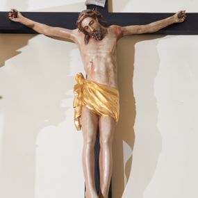 Zdjęcie nr 1: Rzeźba Chrystusa przybita do krzyża trzema gwoździami, ukazana w typie Cristo morte. Ciało w delikatnym zwisie, sylwetka wydłużona o delikatnie podkreślonej anatomii, nogi lekko ugięte w kolanach. Chrystus ma głowę przechyloną na prawe ramię. Twarz szczupła, z wąskim i długim nosem, zamkniętymi oczami, okolona krótką brodą. Włosy długie ze skręconym lokiem spływającym do przodu po prawej stronie, na głowie założona korona cierniowa. Perizonium zawiązane na węzeł na prawym boku, z jednym końcem zwisającym wzdłuż prawej nogi, złocone. Polichromia ciała naturalistyczna. Krzyż gładki, nad głową Chrystusa titulus w formie pionowej banderoli z napisem „IN / RI”. 
