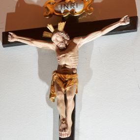 Zdjęcie nr 1: Krucyfiks z rzeźbą Chrystusa w typie Cristo morte. Rzeźba pełna; głowa przechylona na prawe ramię; nogi delikatnie ugięte w kolanach, stopy przebite jednym gwoździem w układzie prawa na lewą. Twarz pociągła, o wyraźnych rysach, okolona jasnobrązową brodą. Na głowie Chrystus ma nimb krzyżowy złożony z trzech wiązek promieni. Sylwetka wychudzona, ciało z silnie zaznaczonymi żebrami klatki piersiowej i mostkiem. Perizonium przewiązane na prawym boku. Nad głową Zbawiciela znajduje się owalny kartusz z napisem „INRI” w polu. Polichromia naturalistyczna w odsłoniętych partiach ciała z zaznaczonymi śladami męki, perizonium złocone, kartusz złocony i srebrzony. Krzyż prosty, drewniany, malowany na czarno.